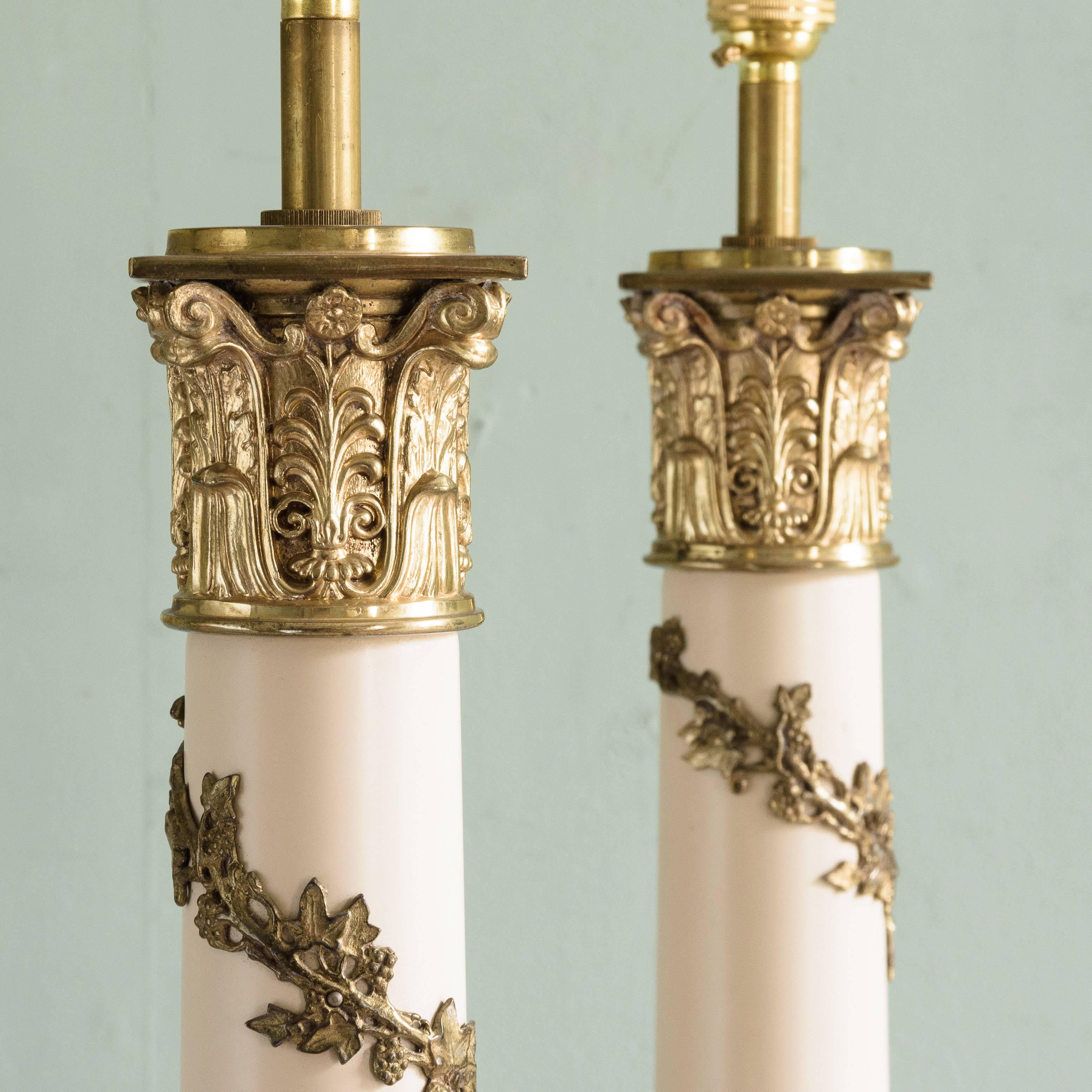 Pair of Corinthian column table lamps, mid-20th century, brass with trailing vine decoration to the shaft, on stepped plinth base. Shades included.