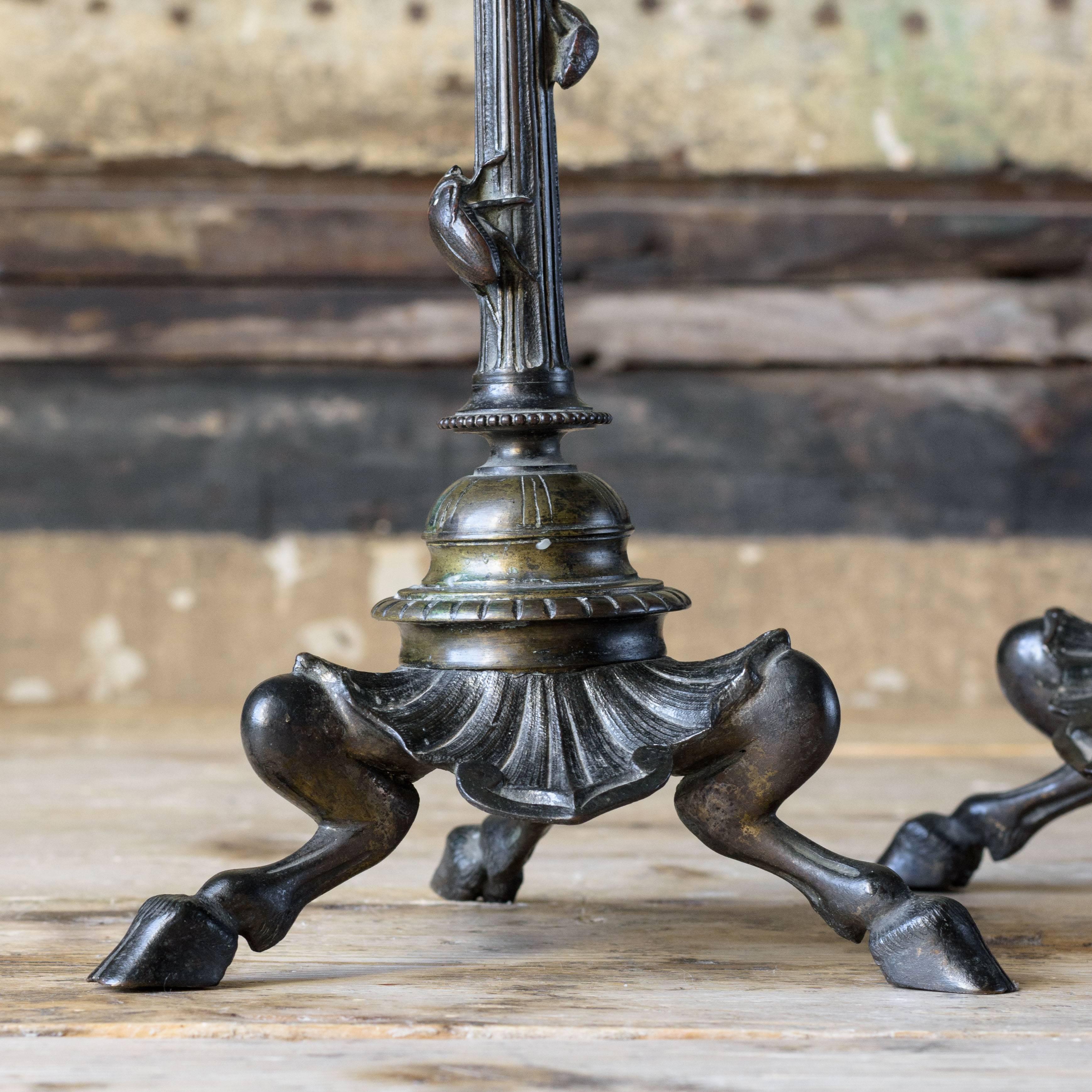 Pair of French bronze candlesticks, circa 1880, the sconces with cast leaf details above tapered and fluted columns with beetles, on cloven hoof triform base.