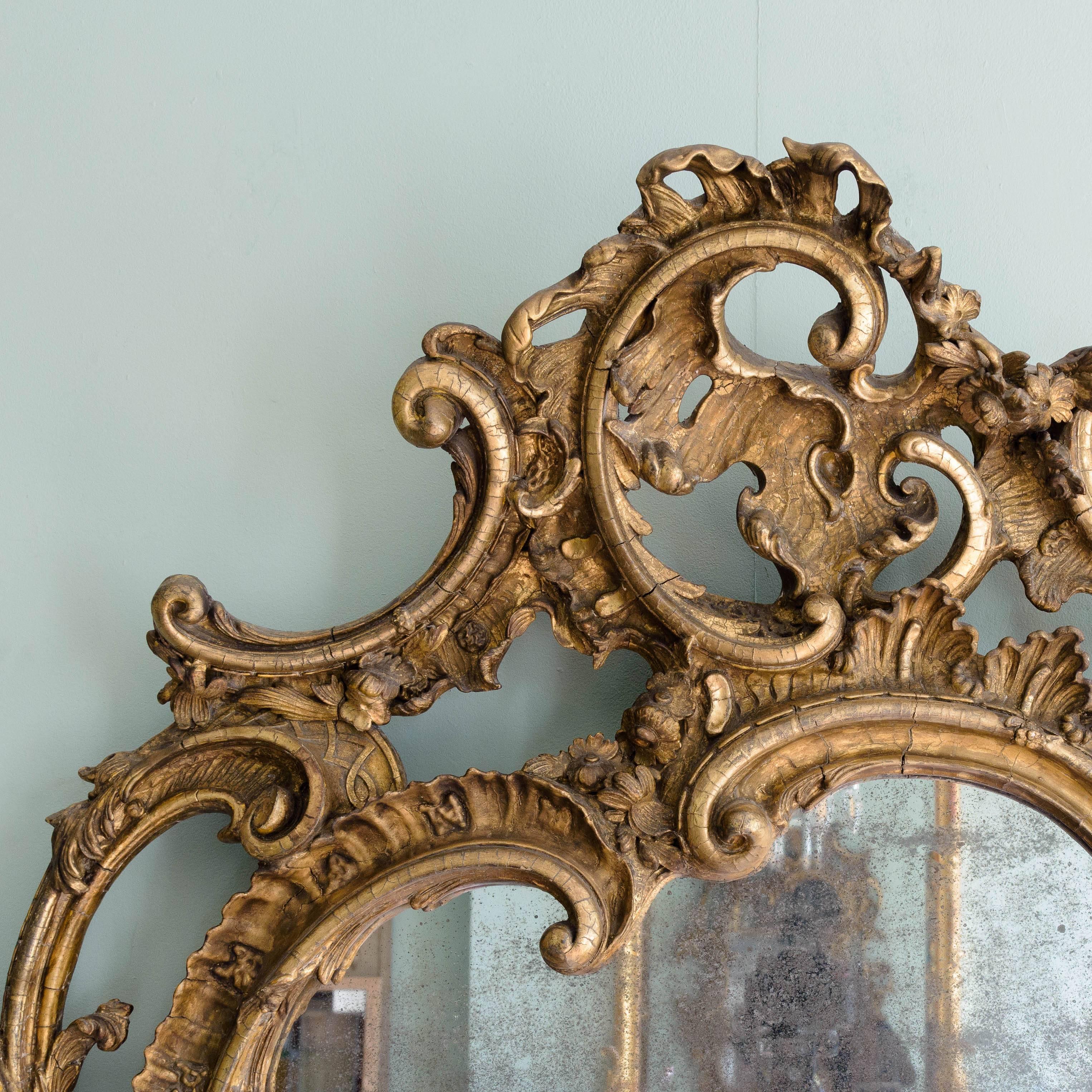 Large 19th century Rococo Revival wall mirror, the well-foxed asymmetric plate surrounded by c-scrolls, the gilded frame comprised of further c and s scrolls, acanthus flourishes and floral motifs.

In fantastic antique condition with both the