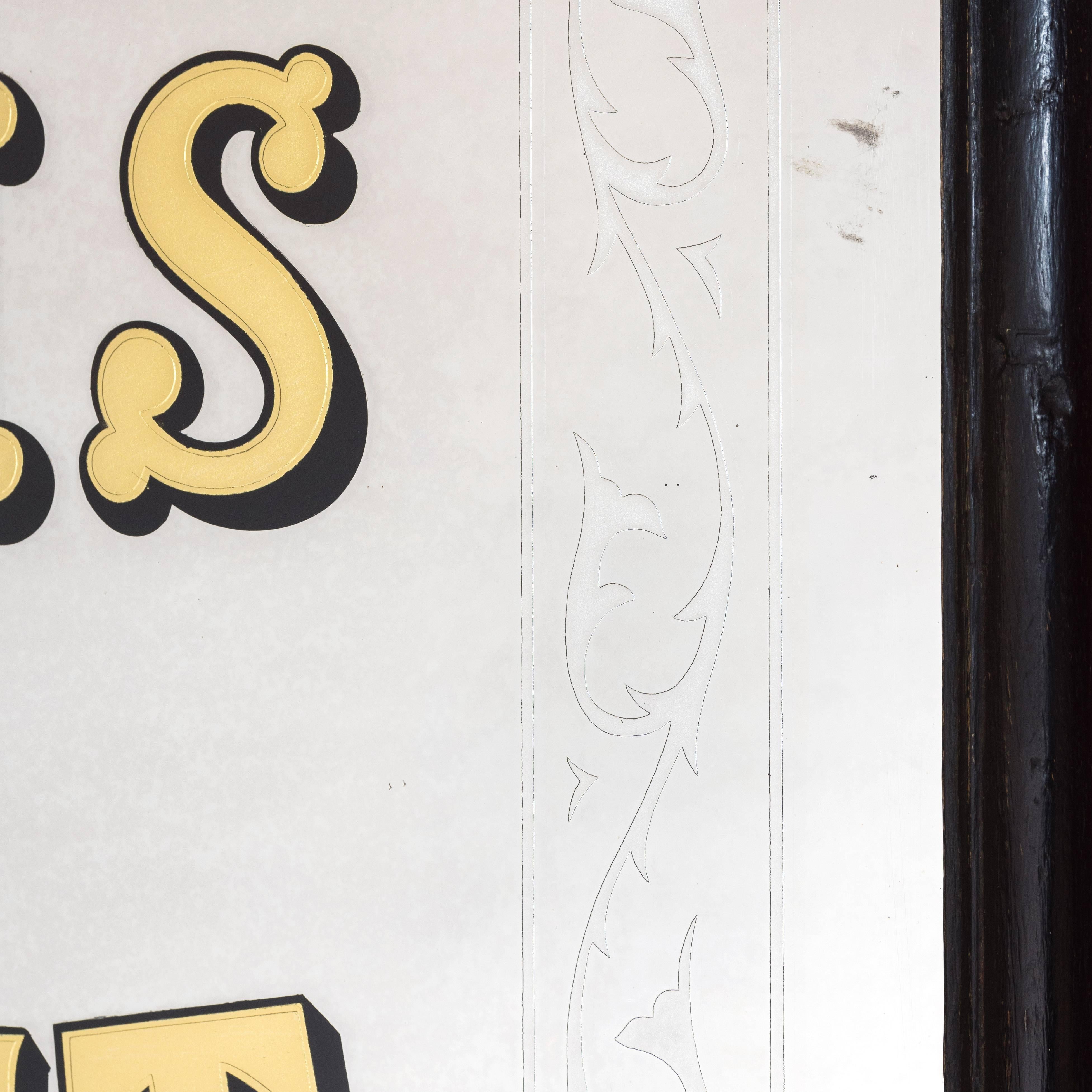 Late 19th century style shop mirror, the rectangular plate within moulded ebonized frame, with gilt and reverse painted drop shadow lettering set within etched border of a foliate design, c.1970.