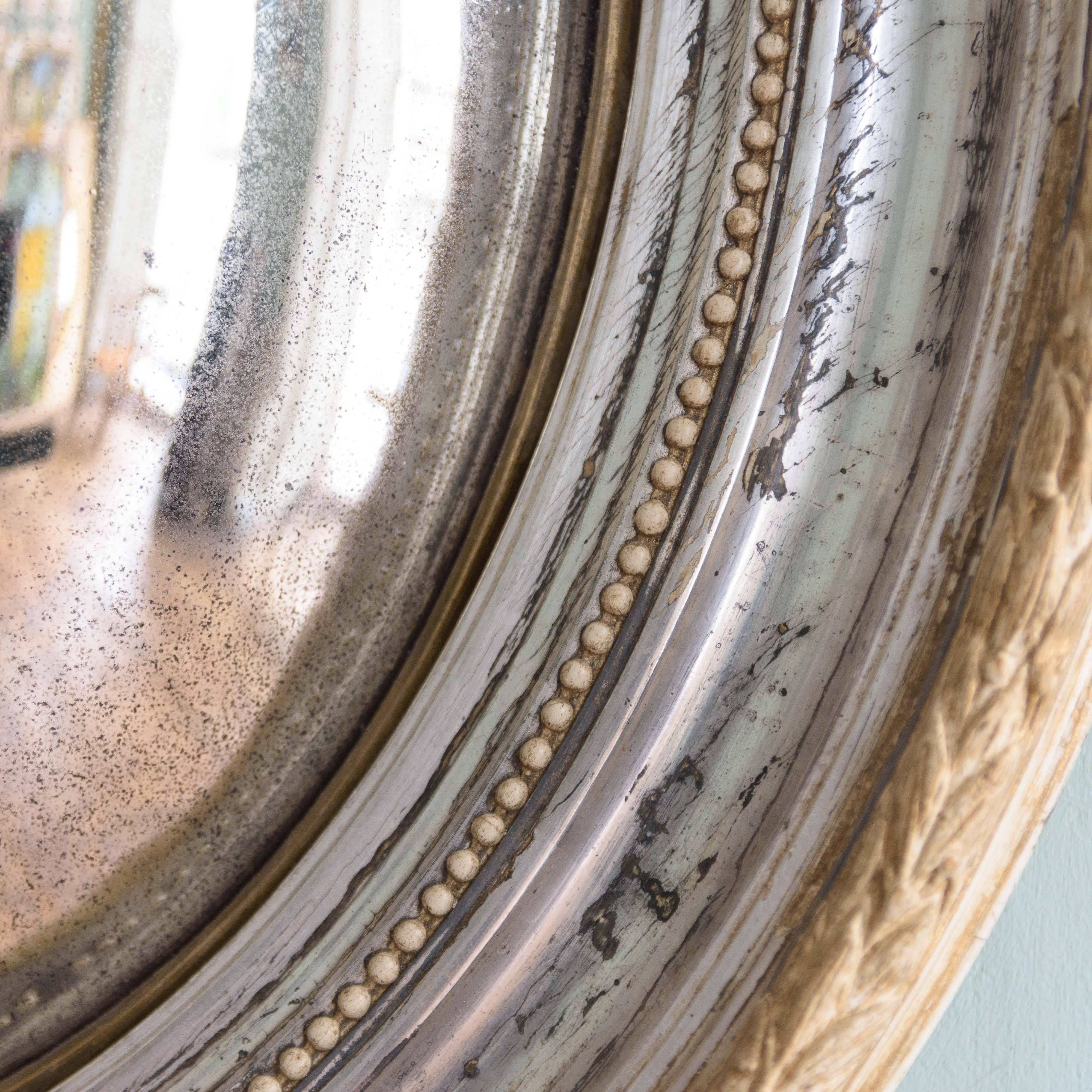 Mid-19th century silver-gilt oval convex mirror, French or Italian, carved wood and composition.
