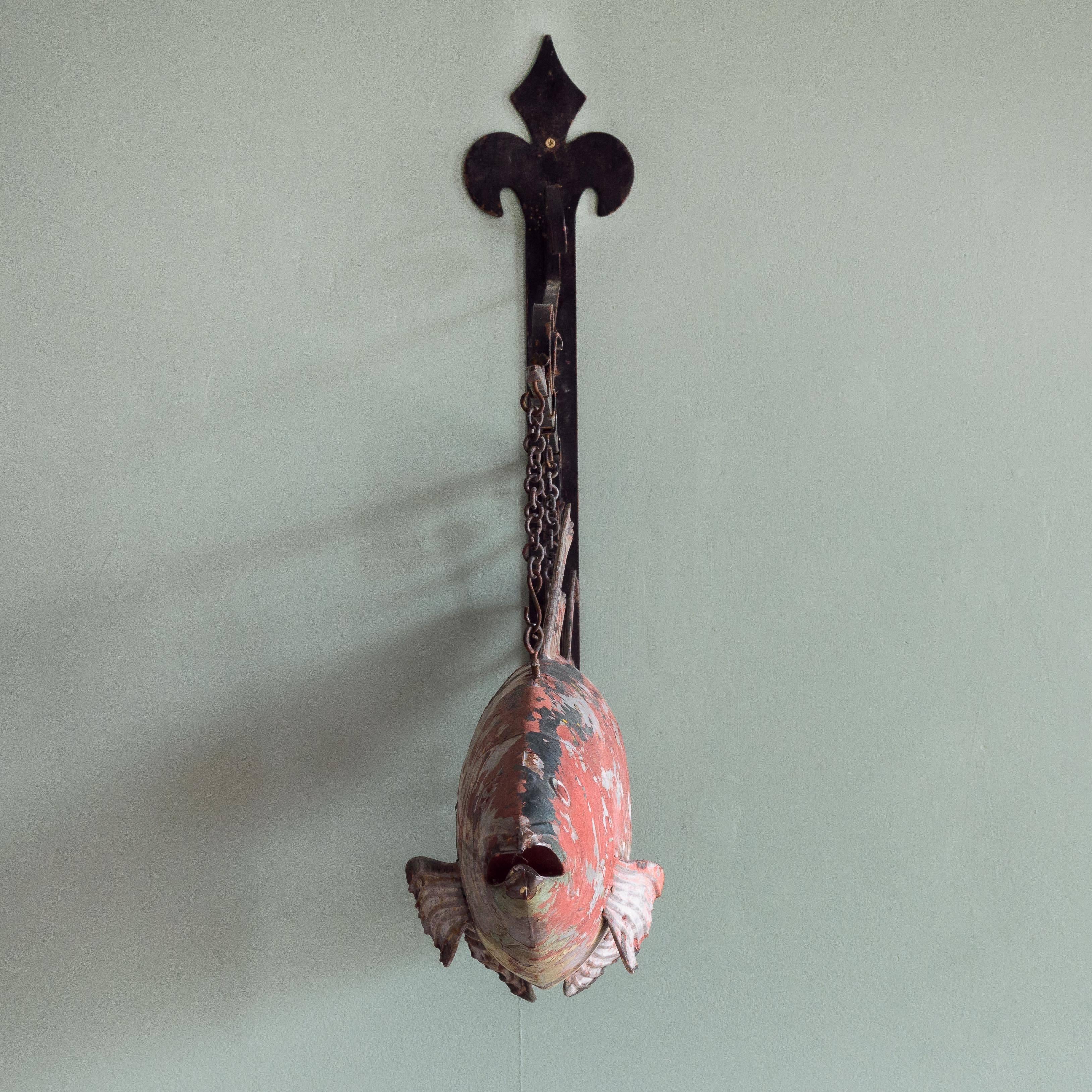 An English tackle shop trade sign, the suspended fish hung from wrought iron wall bracket, the fish with traces of polychrome paintwork, circa 1940-1950.