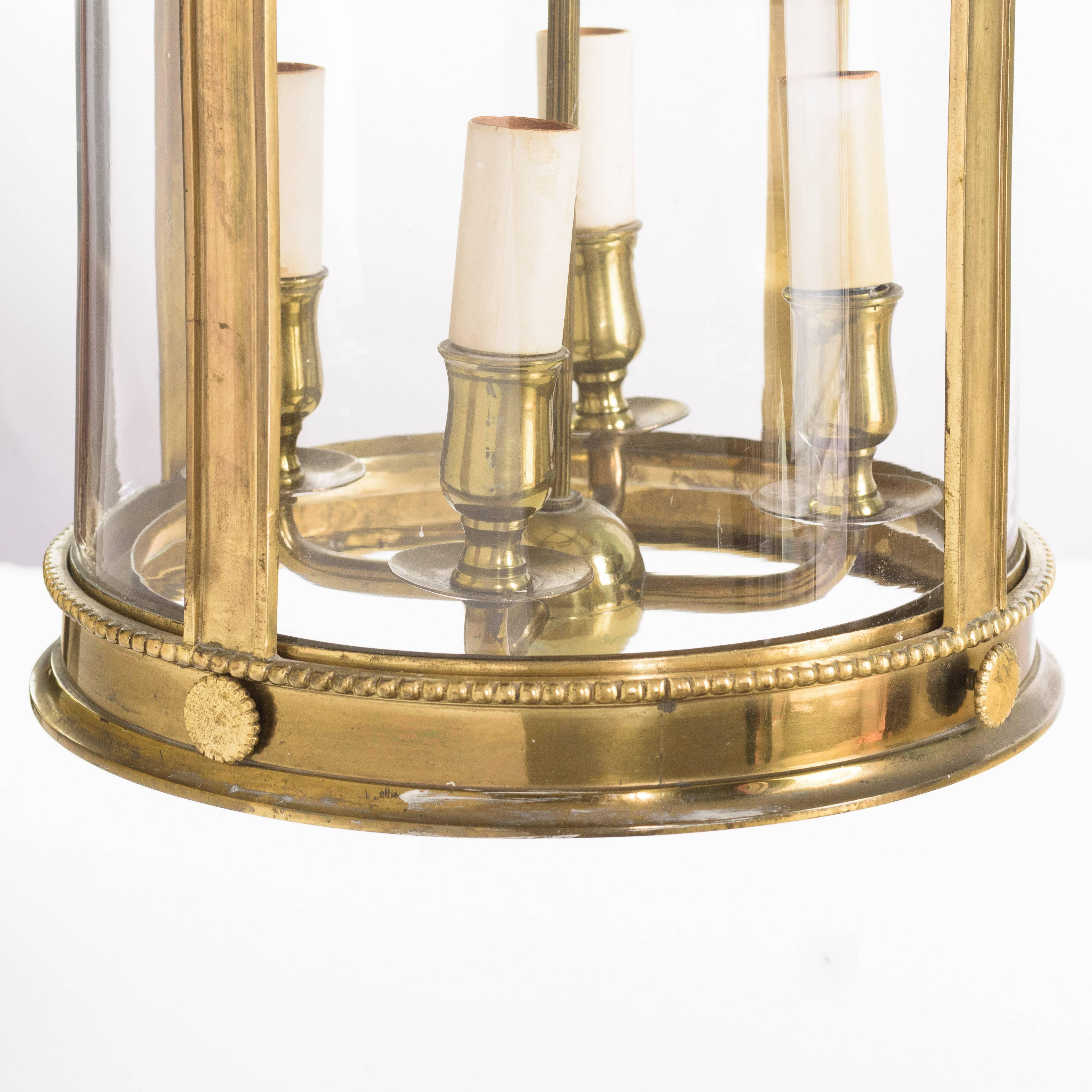 A Louis XVI style brass lantern, 20th century, of cylindrical form hung with garlands of flowers headed by flaming urn finials, with four-light suspended fitting within.

The lantern is in good working order having been rewired and is complete with