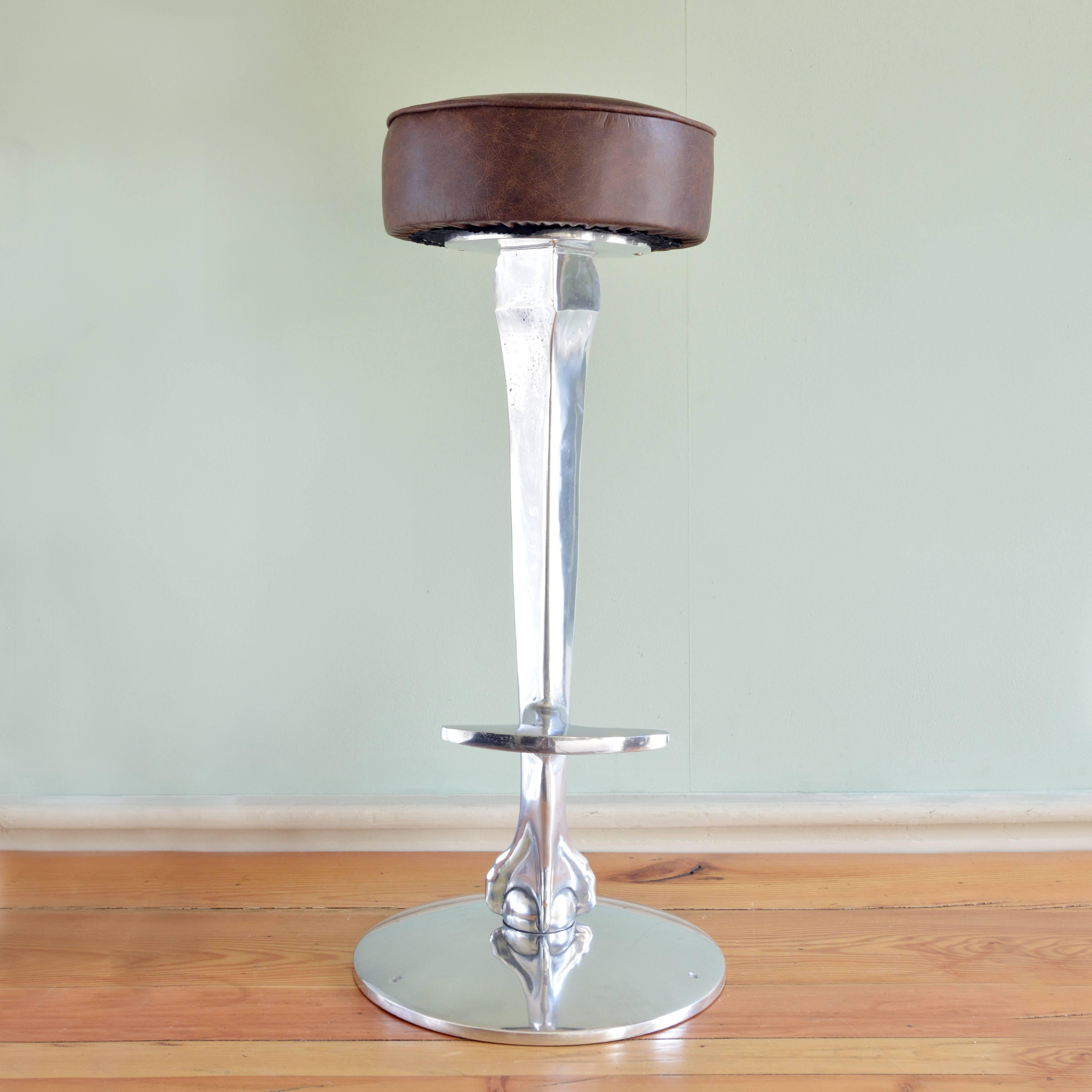 Cast and polished aluminium bar stool bases, of claw and ball design with foot-rest, with brown leather seat pad (three available but as these are reproduction more can be supplied). Available to purchased without the seat pad if required for £435