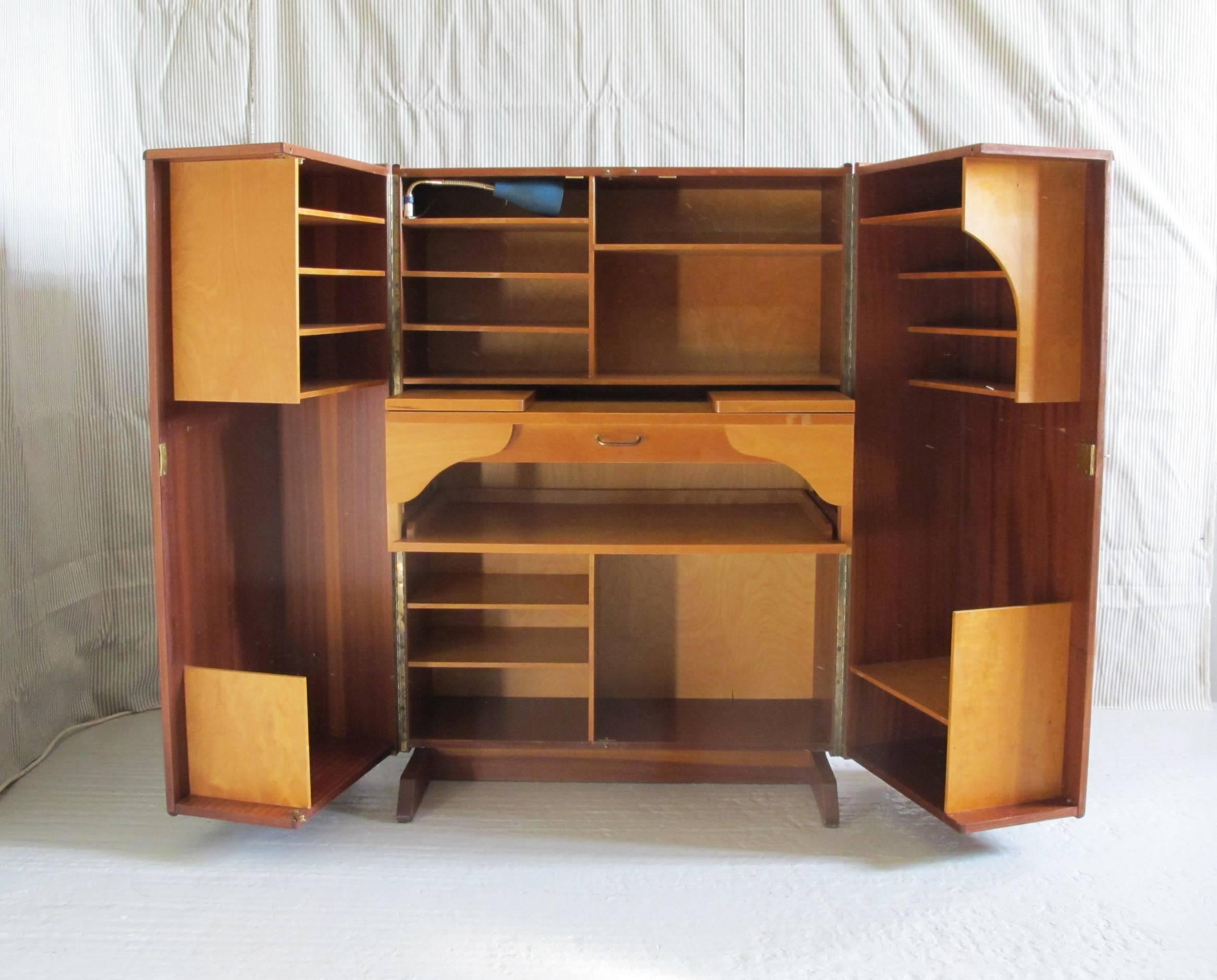 Teak and birch veneered plywood. Includes fold-out desk top with centre drawer, multiple storage shelves and blue gooseneck lamp.