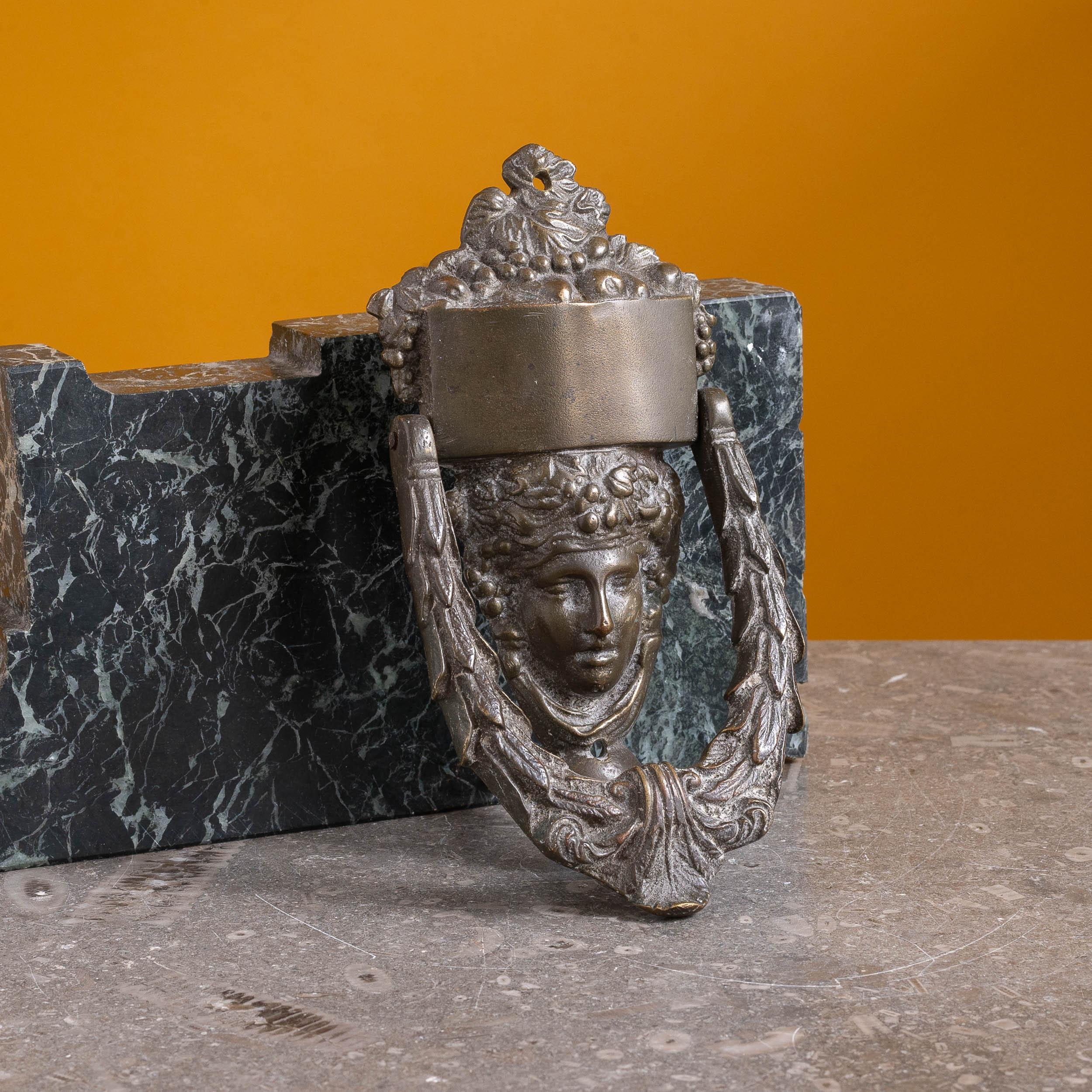 An antique neo-classical patinated brass door knocker, late nineteenth century, in the late eighteenth century style, the Grecian mask adorned with grapes. Examples in the late C18th would likely have had the home owner's name engraved on the