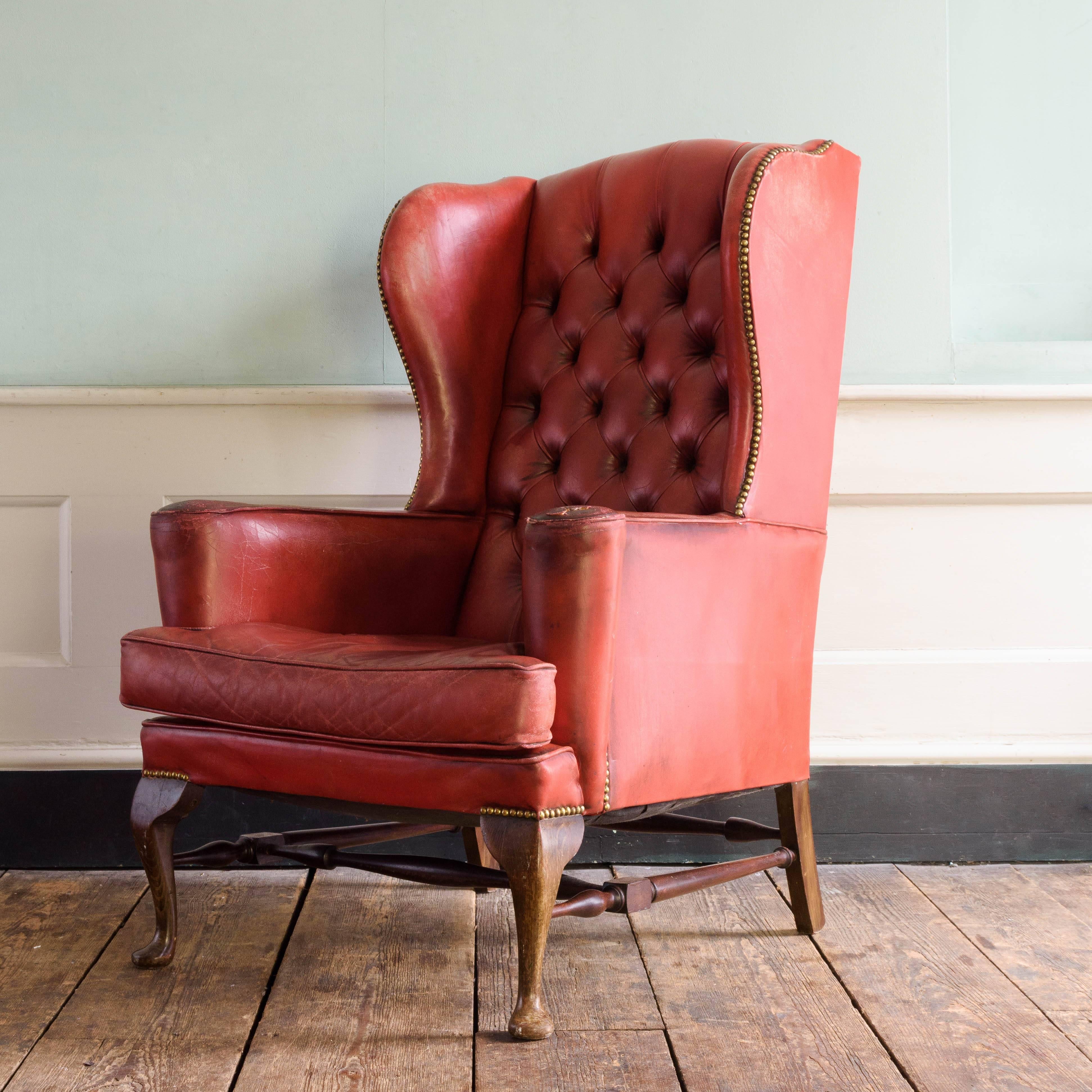 Pair of red leather wingback armchairs, with buttoned upholstery to the back and squab cushion, on cabriole legs.

Dimensions: 116cm (45¾") high, 80cm (31½") wide, 94cm (37") deep.