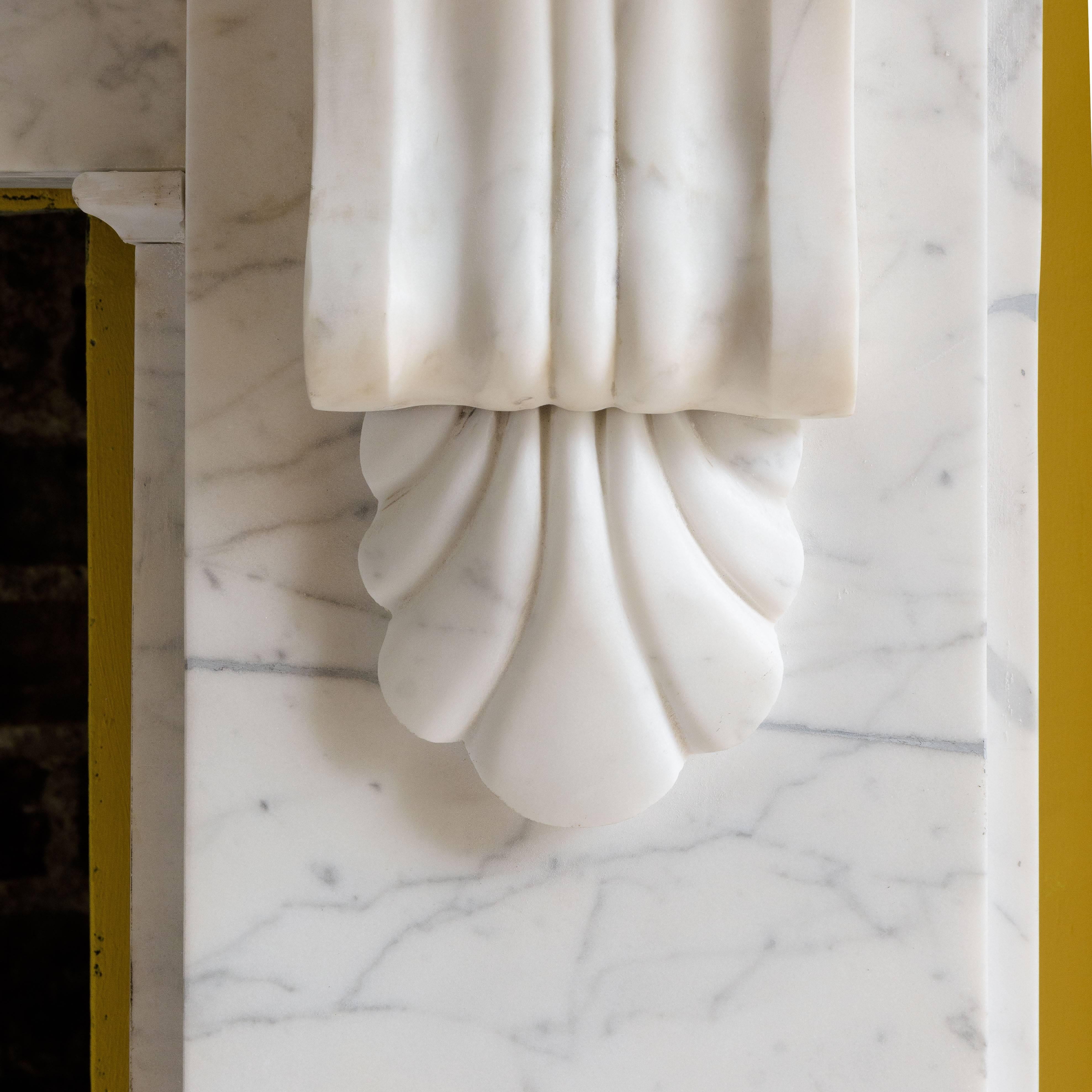 Mid-Victorian Statuarietto marble chimneypiece, the thumb moulded shelf above plain frieze flanked by plain jambs surmounted by corbels with scallops shell below, on plain footblocks.