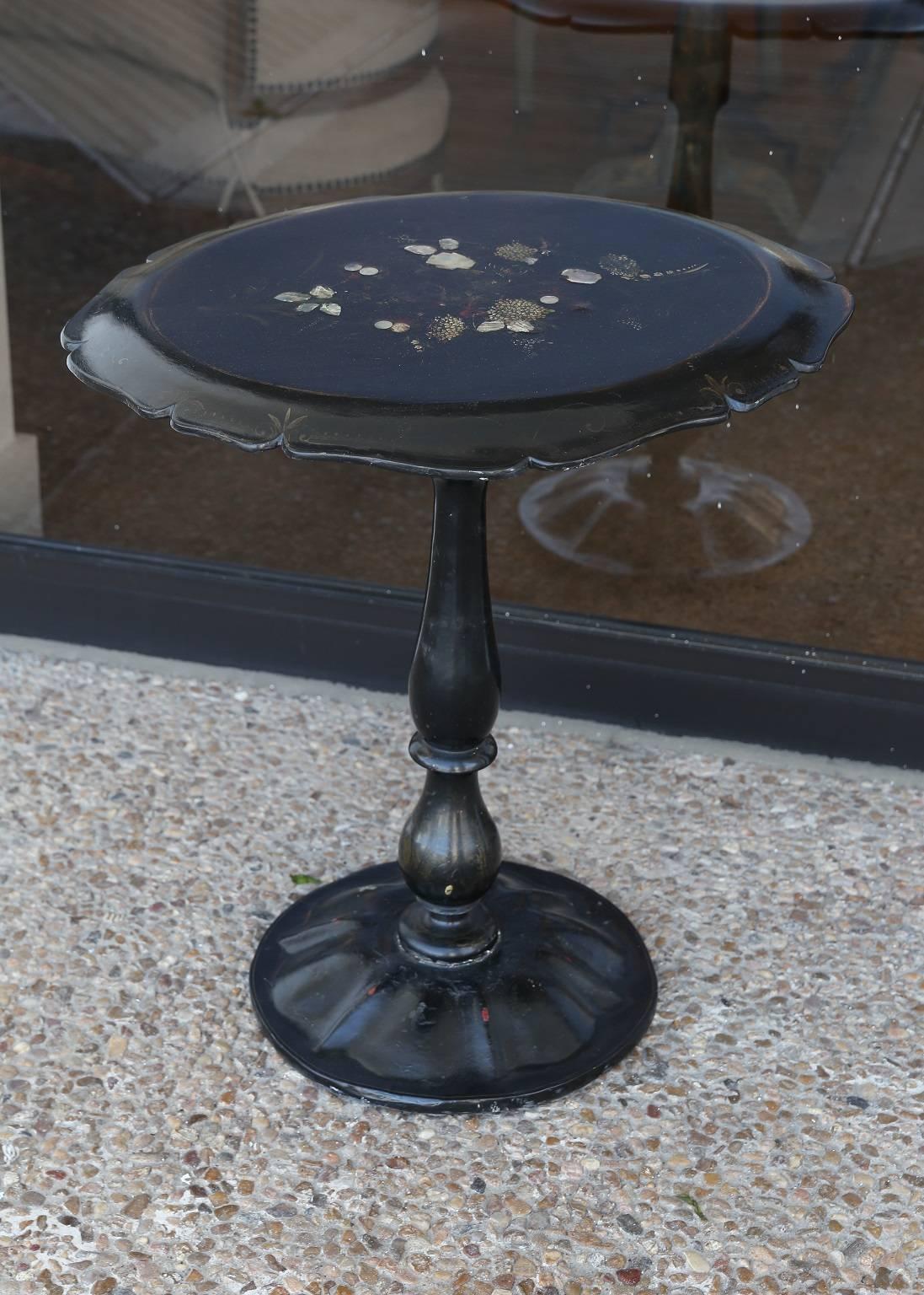 English papier-mâché (papier mâché) table, inlaid with mother-of-pearl floral decoration, with original black lacquer and polychrome painted finish, scalloped oval tilt-top and baluster and ring turned pedestal base.