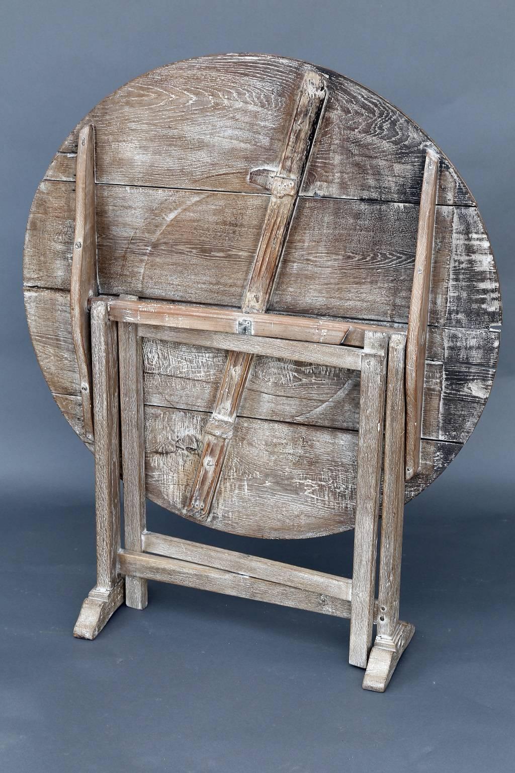 19th century French wine tasting table with a grained grayish-brown patina and remnants of white wash paint. The top that can be positioned vertically for storage, and open flat this table is perfect for a small nook or as a charming end table.
