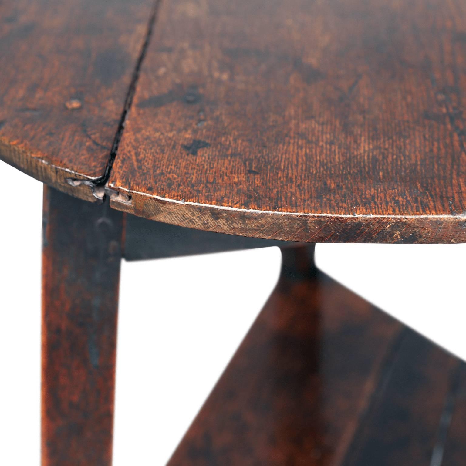 Early English oak cricket table, round top over a lower triangular-shaped beveled-edge shelf, supported by three legs. This excellent example of a late 18th century cricket table retains a handsome patina accrued from over two centuries of use.
 