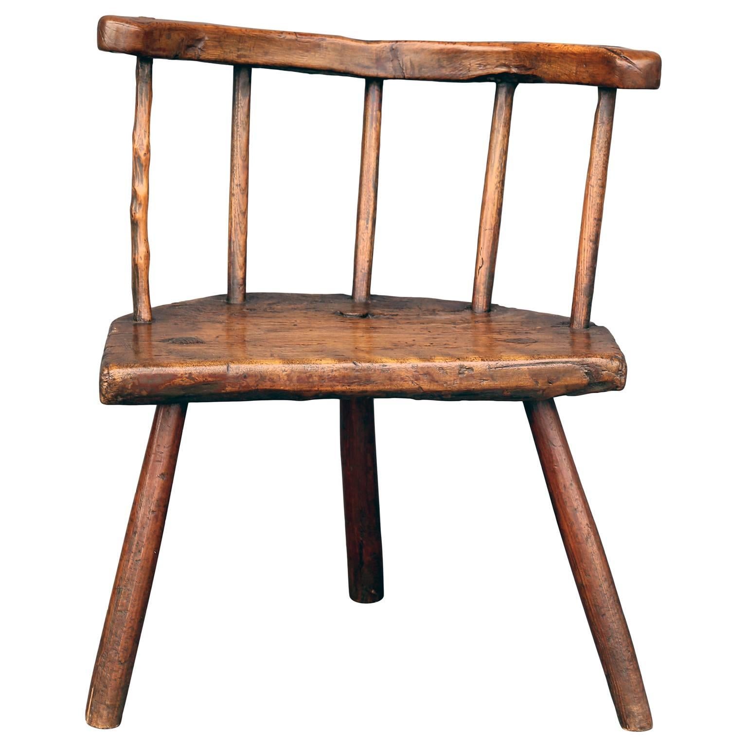 A whimsical, primitive early 18th century Welsh stick chair from ash and elm wood with a well-patinated finish, traces of old dark green milk paint under the horse-shoe arm and morticed construction. Its one-piece horse-shoe shaped arm, three