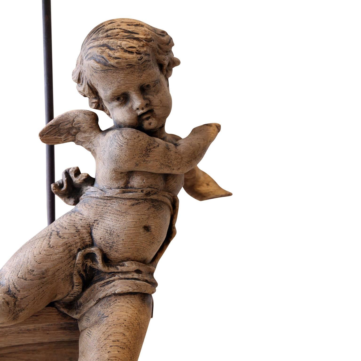 Custom figural table lamp from an 18th century carved putti (cherub) fragment in oak. The fragment is a cool, pale naturally semi-bleached oak. Newly-wired for use within the USA. Includes a complementary linen rolled-edge shade. Lamp measurements