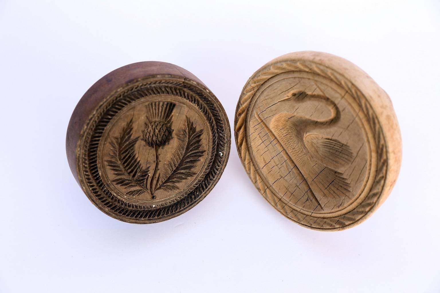 Two Welsh butter prints: 19th century lathe-turned sycamore, hand-carved stamps. The carved swan motif print measures 3.75 inches high by 4.5 inches diameter and the carved flower motif print measures 2.75 inches high x 4 inches diameter. Genuine