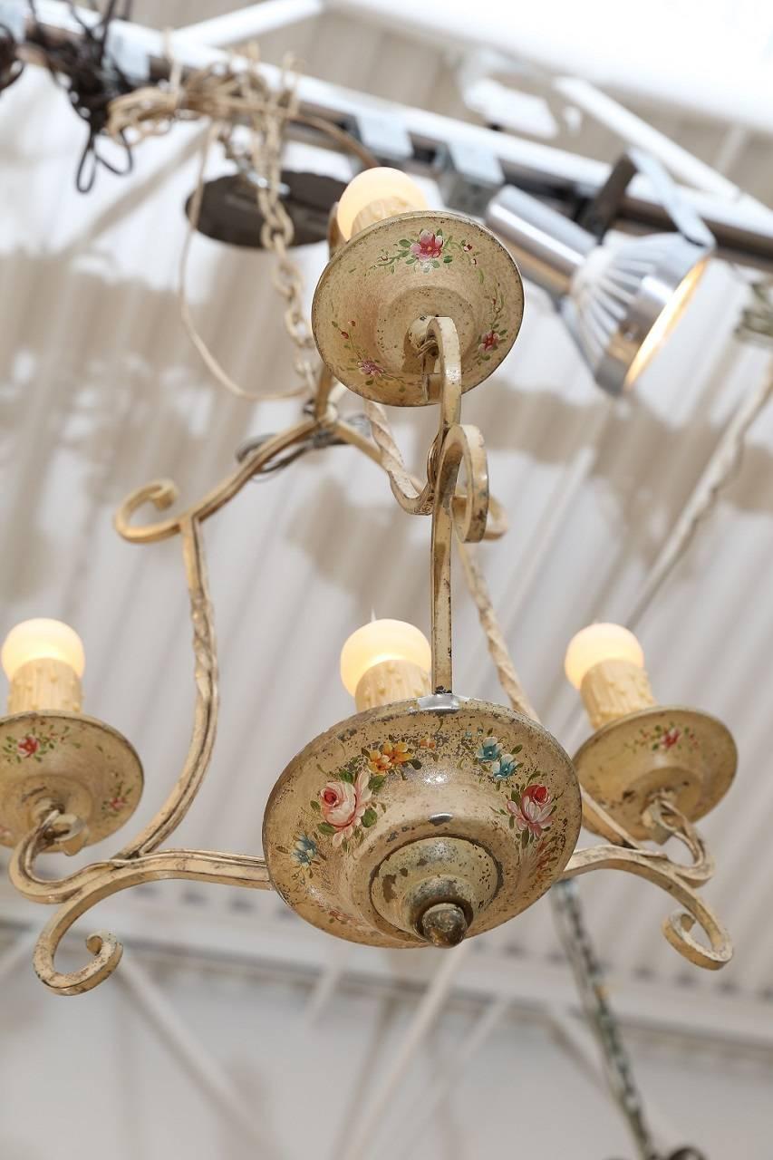Vintage painted iron cage-style chandelier with four lights, circa 1930s. The chandelier's central Edison-base light is surrounded by three Edison-base lights. All lights sit in bobeche cups decorated with a floral motif. Newly wired to UL standard