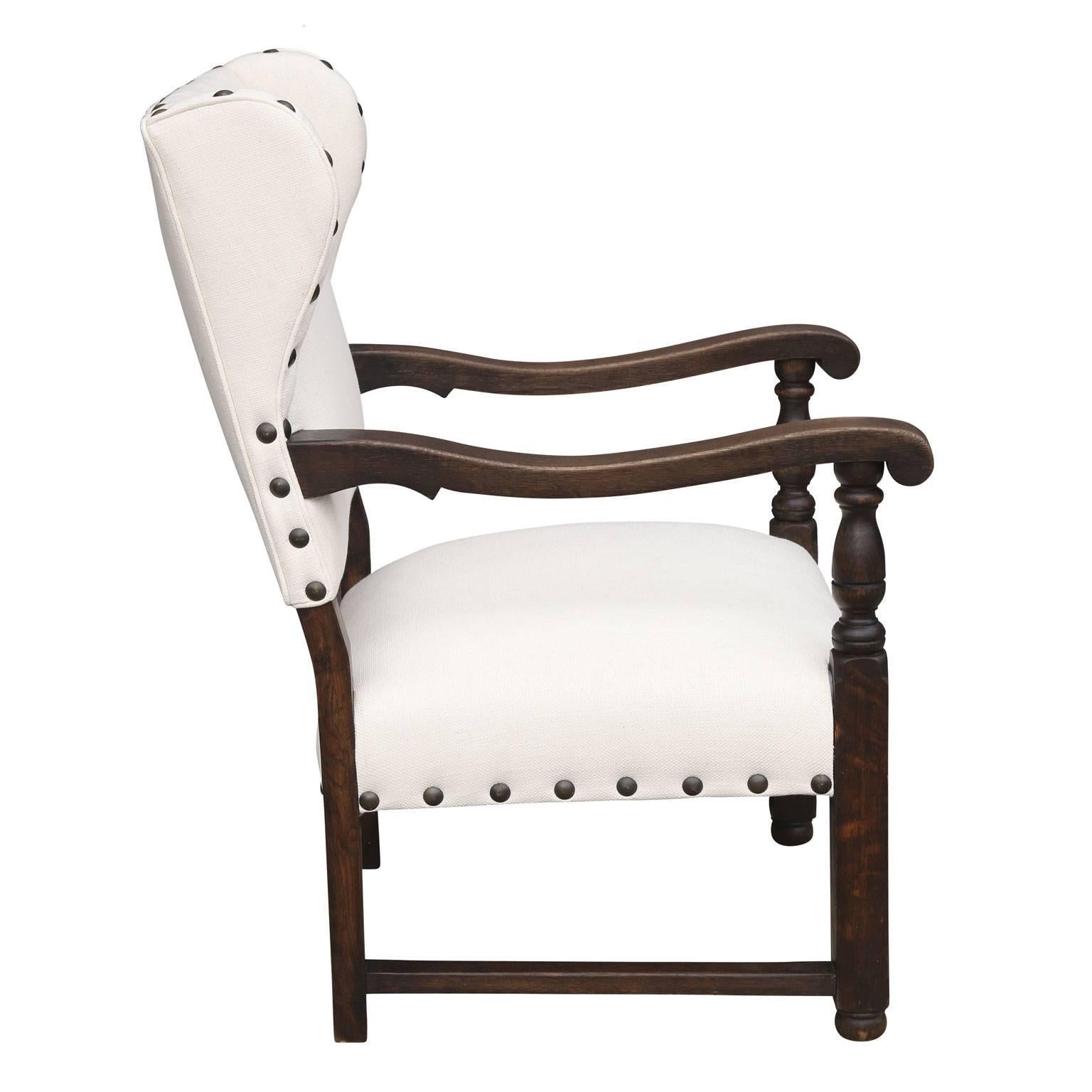 Early 19th century wingback chair from France, circa 1830-1850. This deep-seated wing chair's unusual proportions are the result of the original back shortened at a later, but early date, with ears (cheeks) subsequently added. This fireside chair is