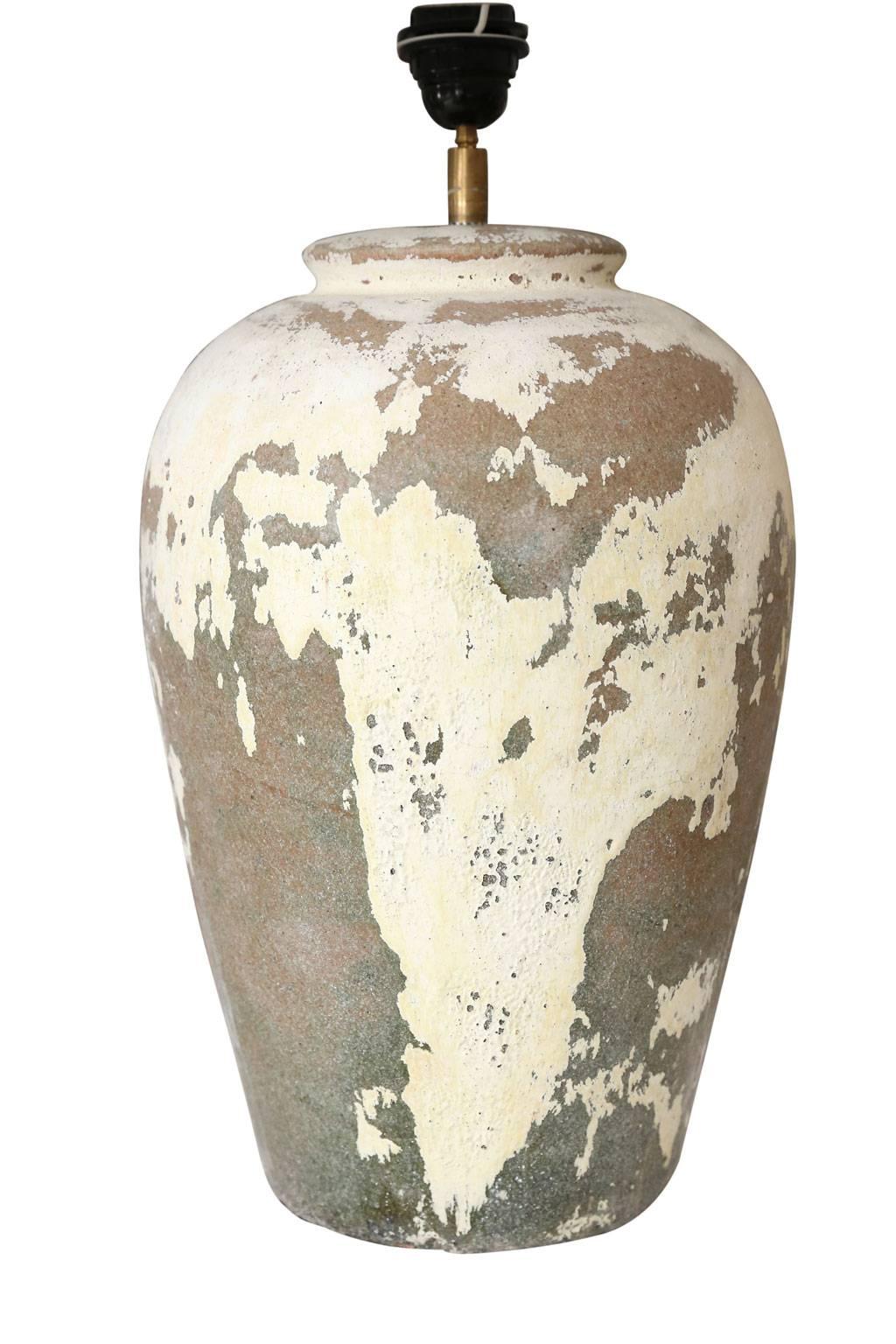 Pair of ceramic grayish terracotta color vases with remnants of an off-white plaster finish, newly wired to as custom table lamps. Each lamp comes with a complementary rolled-edge linen shade (measurements include shade), and both lamps are sold