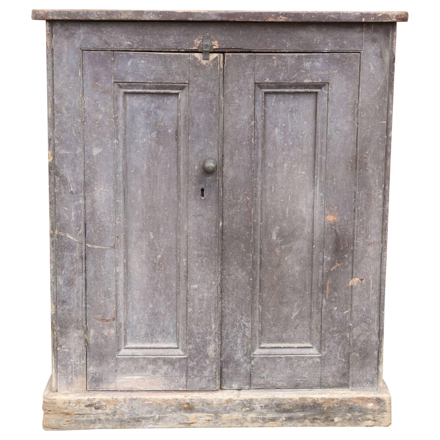 Painted two-door cabinet (cupboard) has an original oxblood painted finish that's accrued a gorgeous grayish patina over the decades. The cabinet's construction is predominately mortise and tenon in pine, sides are paneled and its interior holds a