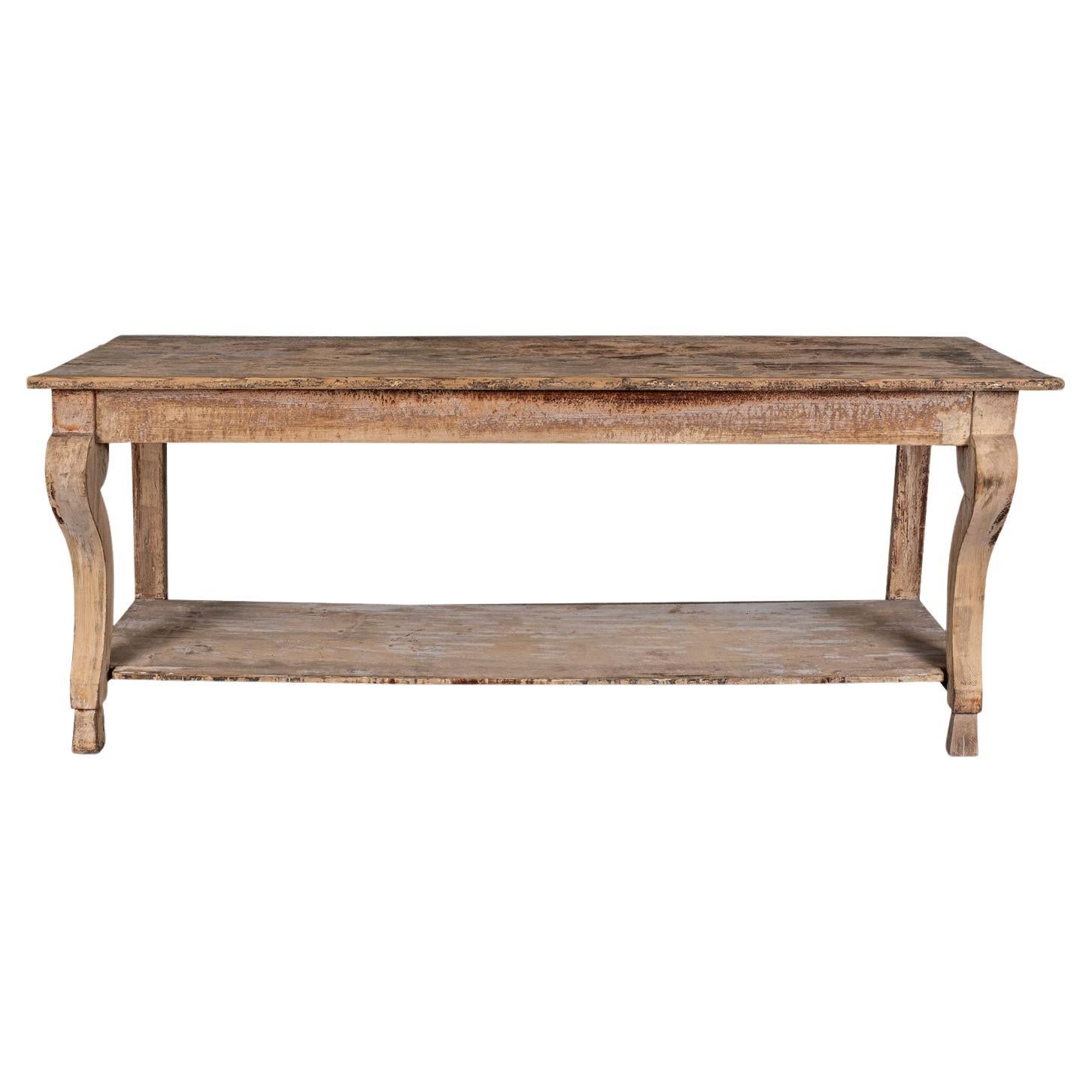 Large-scale painted console table, designed in neoclassical style. Large-scale long console, with a full-length under-shelf and hoof-shaped front feet. Remnants of early paint decorate console's scraped back surface.

Note: Regional differences in