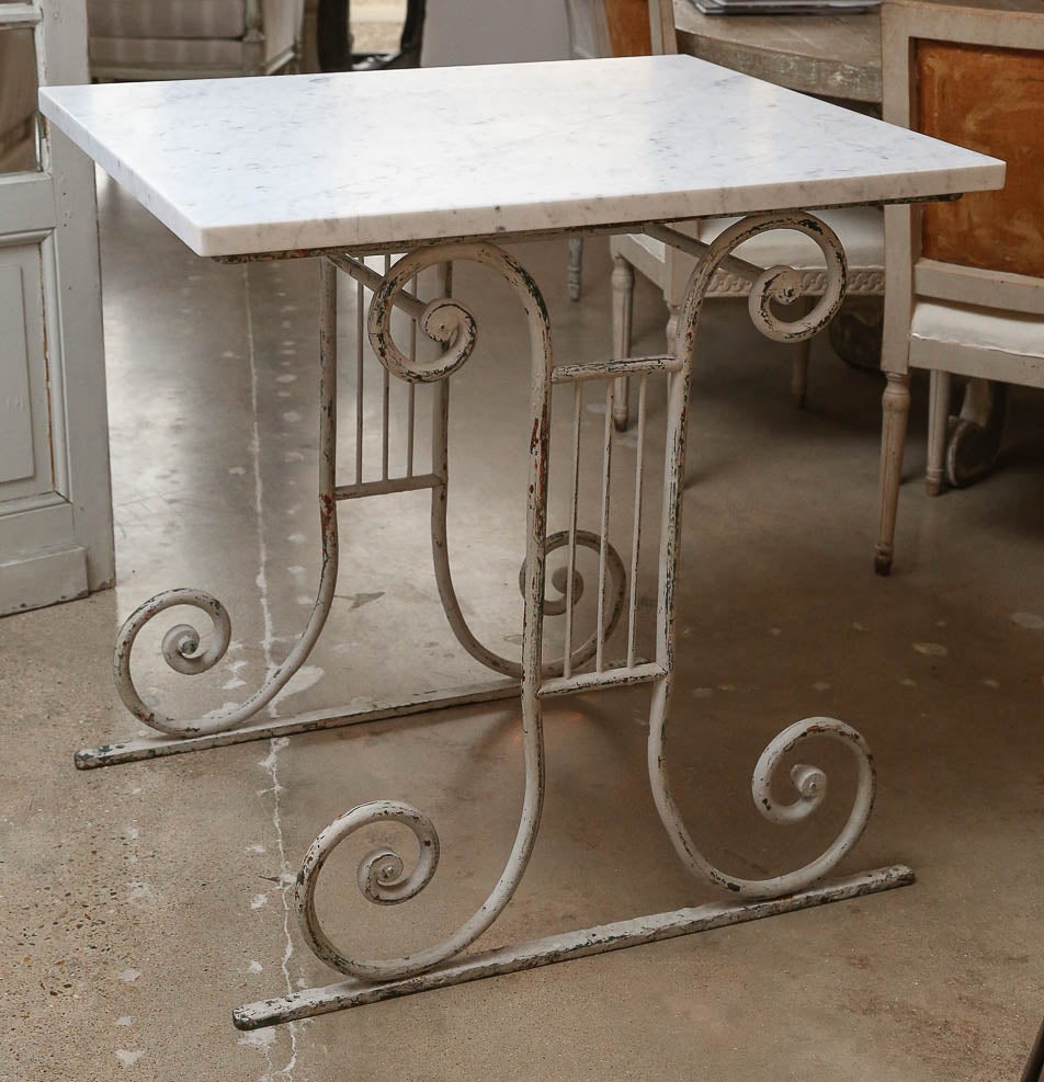 Marble-top white-painted base table (French butcher's table), dating to the late 19th century. Later Carrara marble top raised upon a painted scrolled iron base. Table de Boucherie.