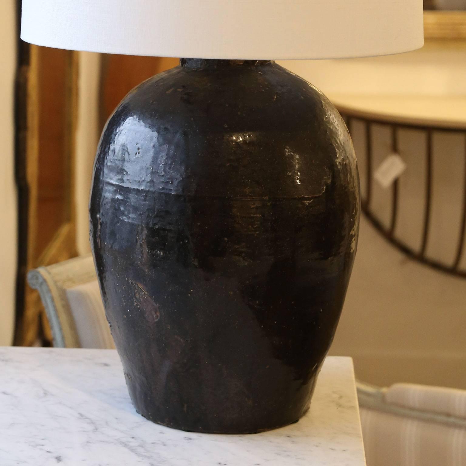 18th century (or earlier) dark chocolate color glazed terracotta French urn, newly wired as a custom table lamp with a rolled-edge linen shallow drum shade. This lamp is French-wired to avoid drilling into the piece, so it may be reused as an urn or