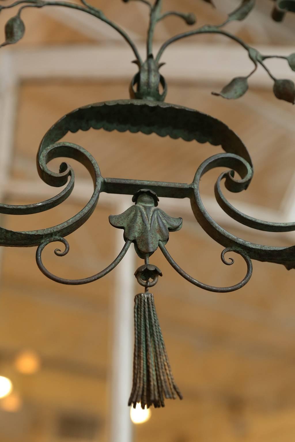 An exceptional French wrought iron chandelier in its original green painted finish, that acquired a desirable patina over years. Newly wired for candelabra size bulbs, this chandelier features four beautifully scrolled arms supporting scalloped-edge