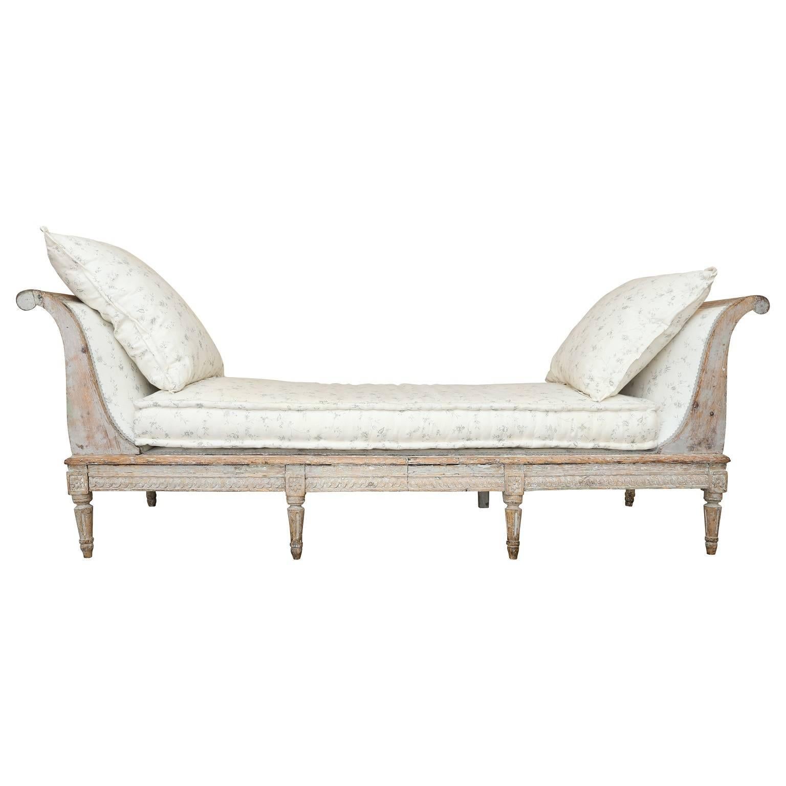 18th century Gustavian daybed, decorated with gracefully curved arms, a carved guilloche motif along the front and side rails, and legs adorned by carved rosettes and fluting.
 