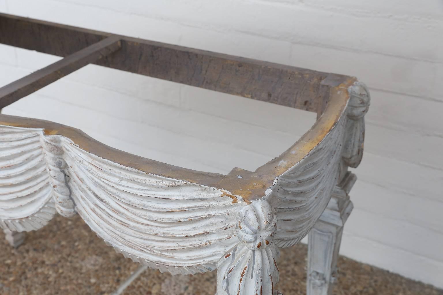 18th century Italian console table with faux marble top, finely carved drape-shaped apron and four tapered legs, in later paint.