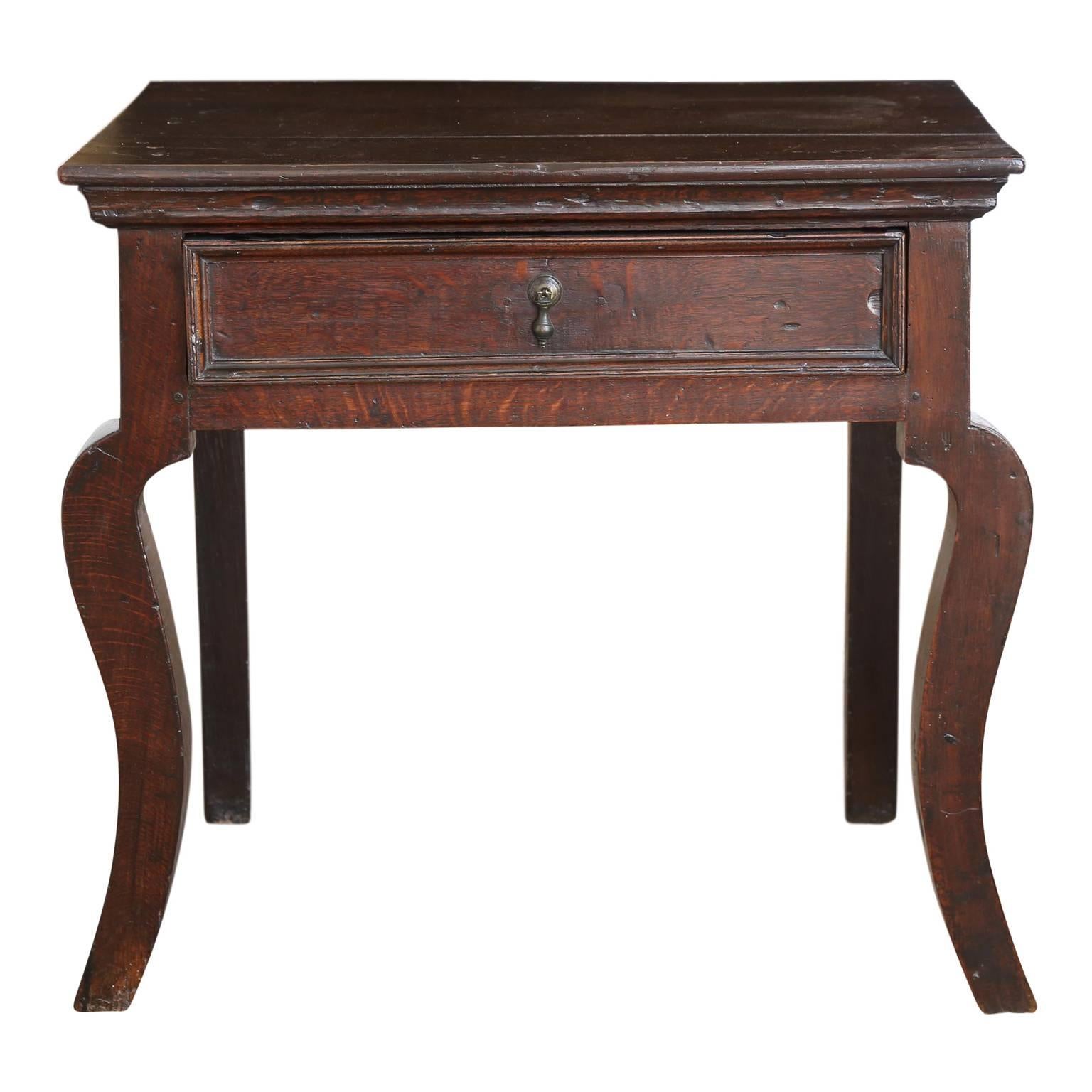 Brown English oak side table with single (trap-door bottom) drawer and front legs which are cabriole-shape silhouettes. Constructed in a vernacular manner, circa 1860-1870 using 18th century elements (probably to sell to a 19th century antique