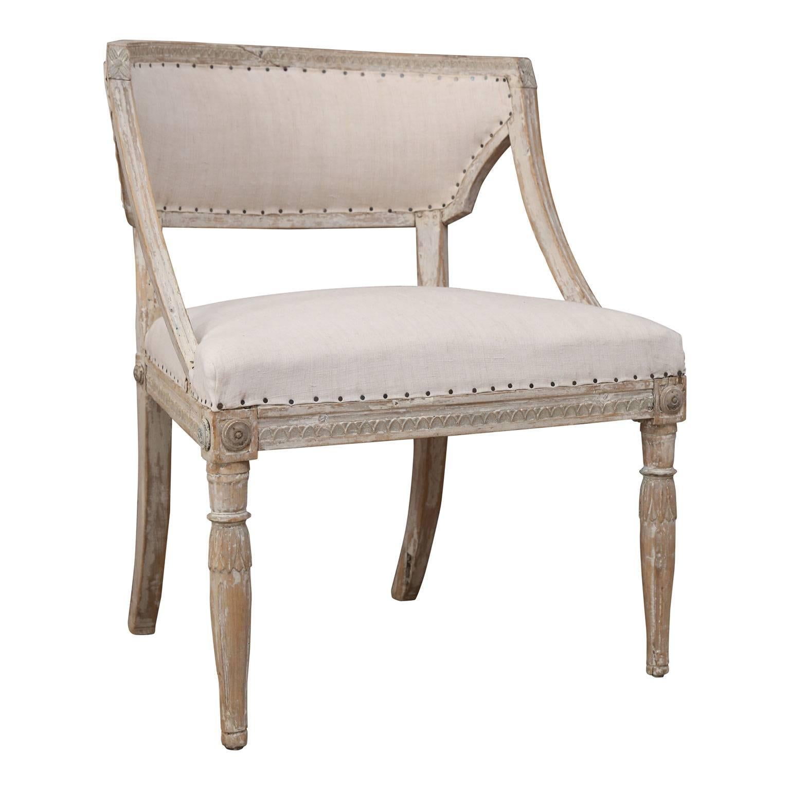Pair of early 19th century Gustavian style barrel-back tub chairs from Sweden, in an attractive, scraped-back old paint finish and newly upholstered in linen. Carved lotus motif decoration adorns the back, apron and upper portions of the turned,