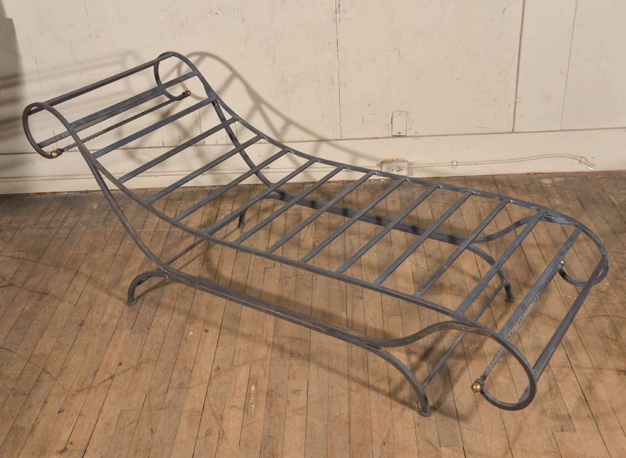 Distinctive steel chaise longue, finished as forged iron and adorned in brass detail. Sold with newly-made tie-on upholstered cushion in antique hand-loomed French thistle and natural canvas. All listed measurements include cushion.