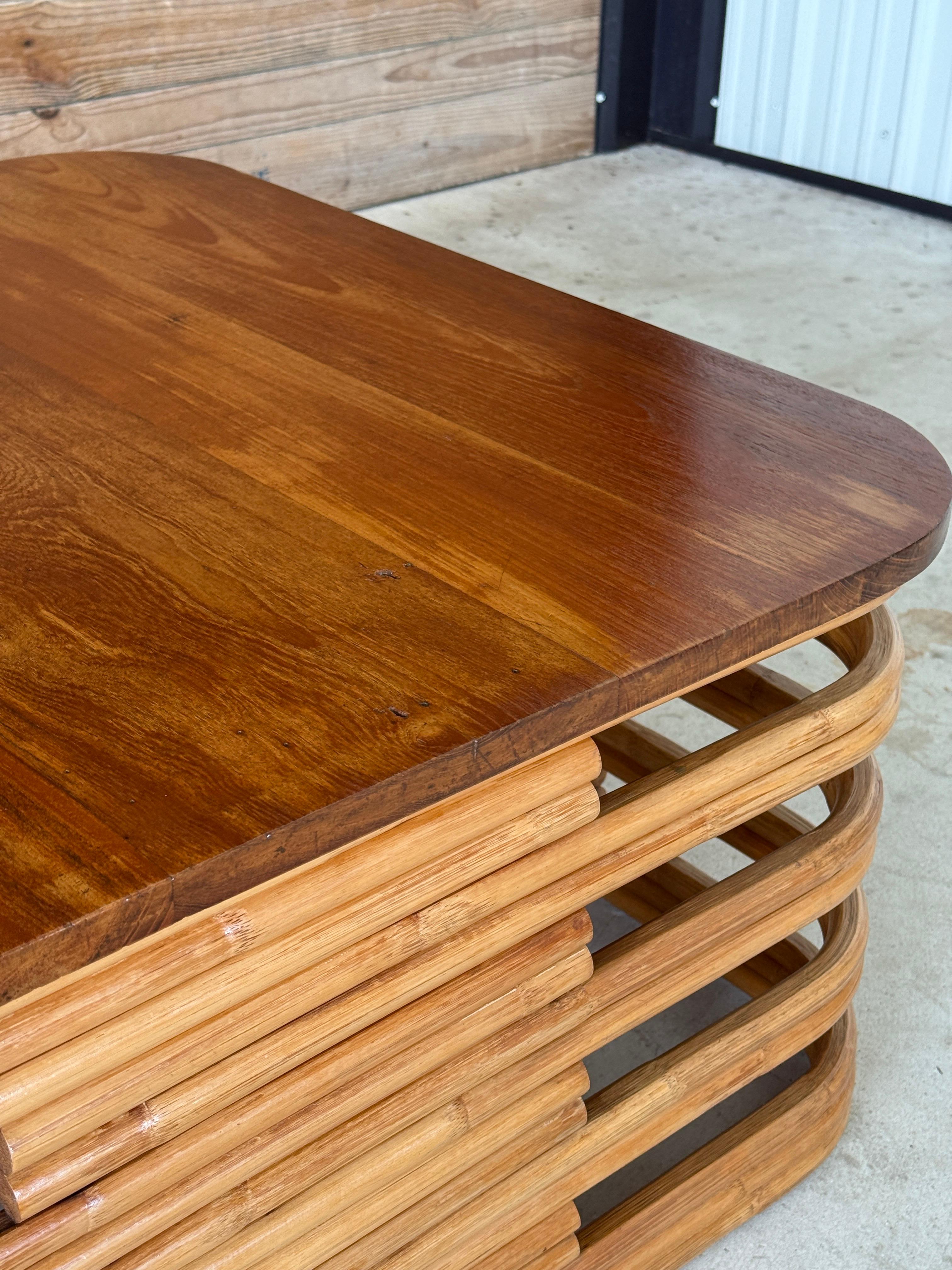 Exemple frappant du design classique de l'ancienne Floride, cette table basse du milieu du XXe siècle présente une base sculpturale en rotin empilé associée à un riche plateau en bois d'acajou massif. Restaurée par des experts, cette pièce évoque le