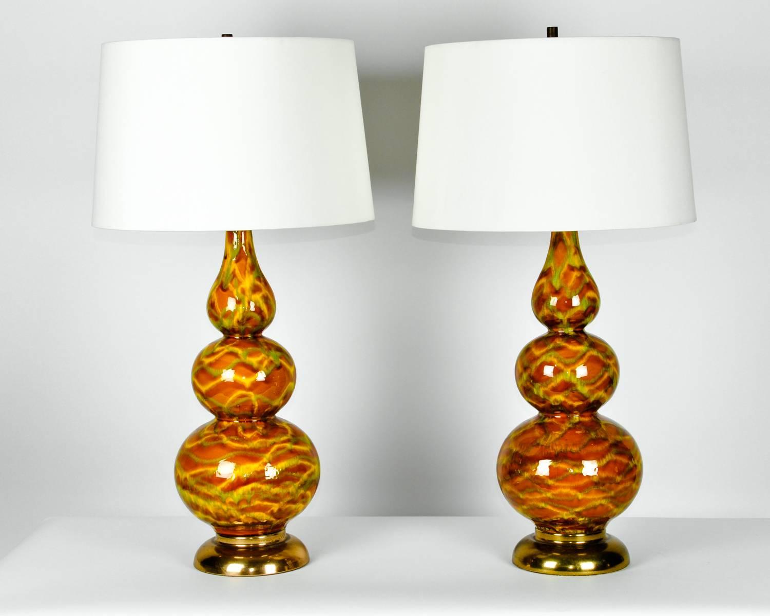 Vintage porcelain pair table lamps with brass base. Each lamp in excellent working condition. Each lamp measure 32 inches high x 8 inches diameter. Each lamp comes with a round drum silk exterior shade 11