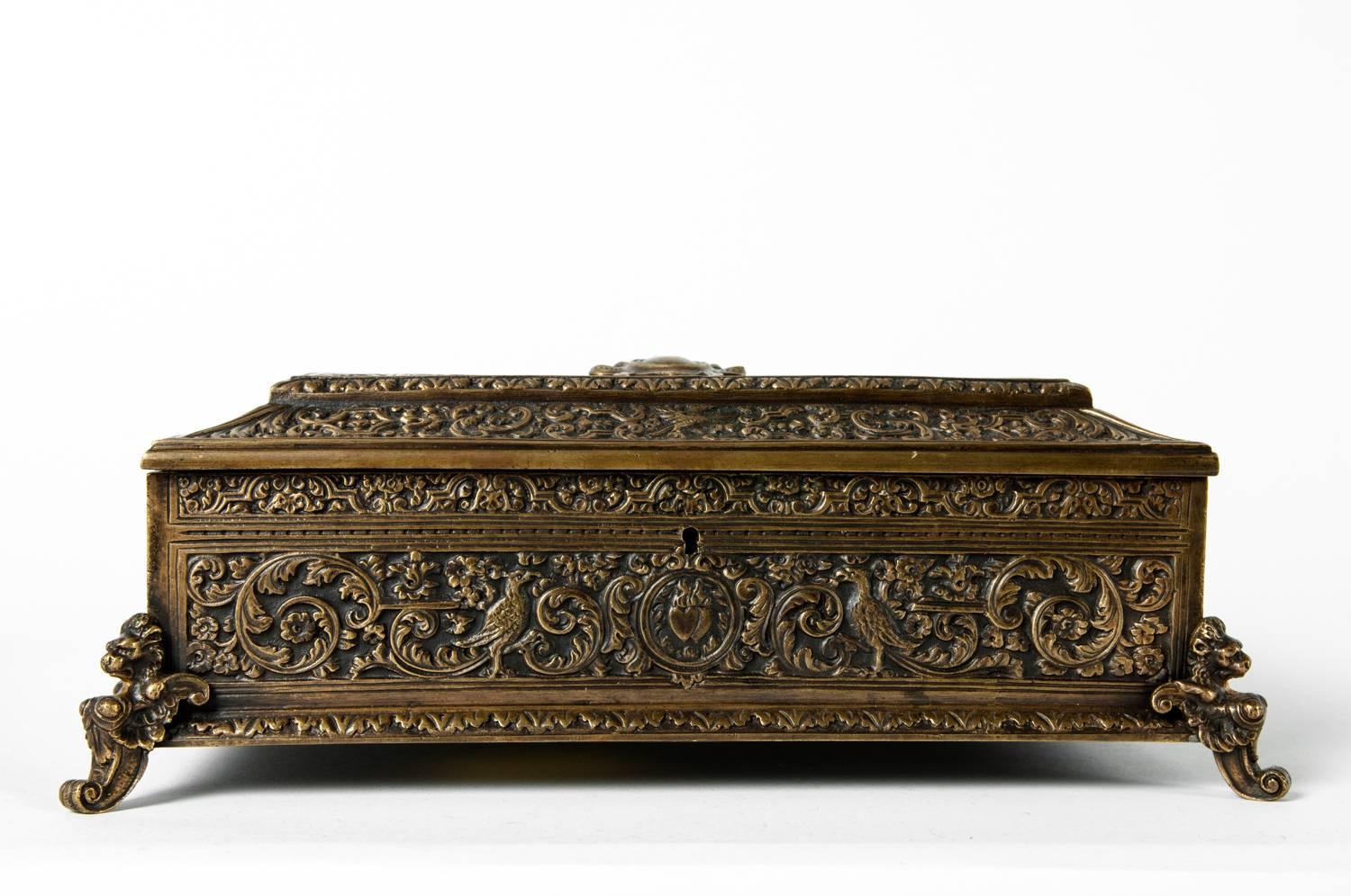 Antique French brass embossed detailing decorative footed box with crest decorative hand chase work and resting on four lions heads. The box measure 11 inches long x 9 inches width x 4 inches high.