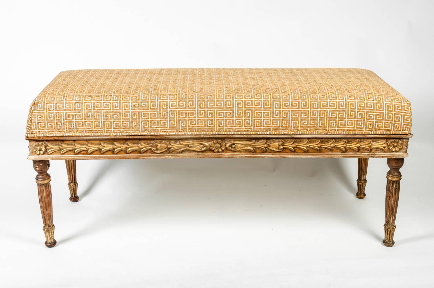 Vintage carved wood vanity bench with gilt finish. Newly upholstered in gold raised velvet fabric with Greek key motif. This piece is in excellent Study condition . The bench measure 47 inches Width X 20 inches High X 18 inches Deep . 