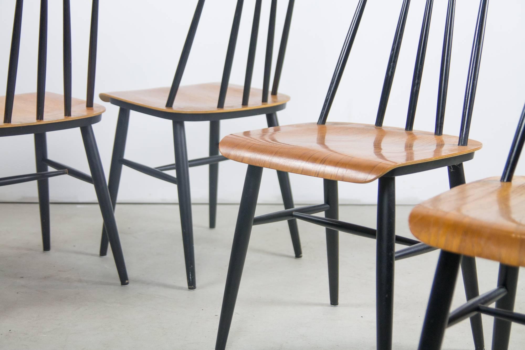 A set of four Fanett dining chairs by Ilmari Tapiovaara. The natural wood of the bent-plywood seats and top rails Stand out as set against black lacquered legs, stretchers and spindles. These do much to retain a traditional Scandinavian form while