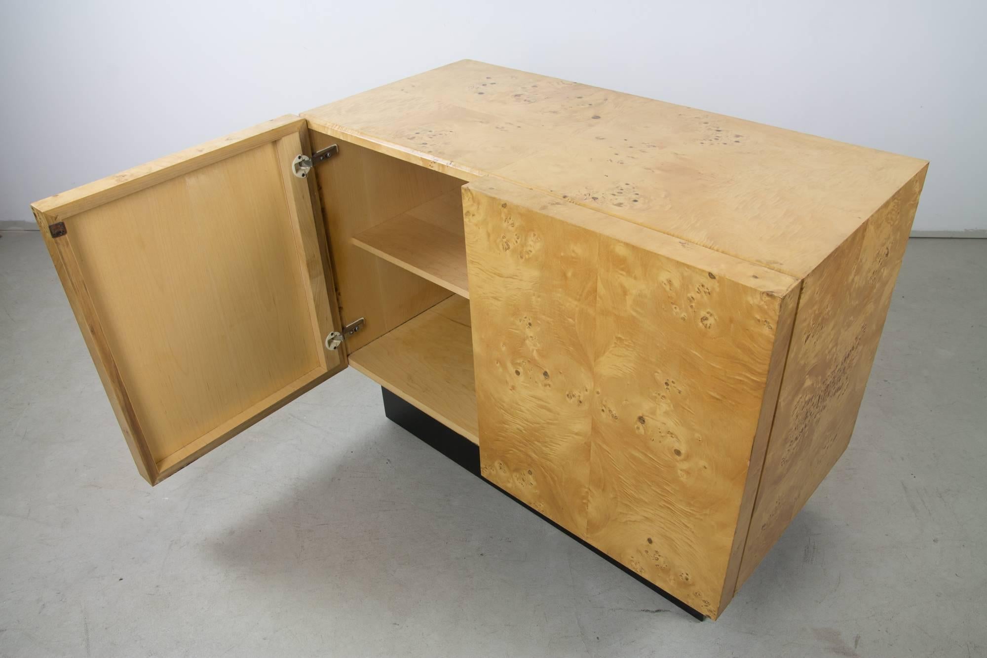 An excellently proportioned and figured two-door cabinet covered in olive burl veneer atop a black plinth base attributed to Milo Baughman.