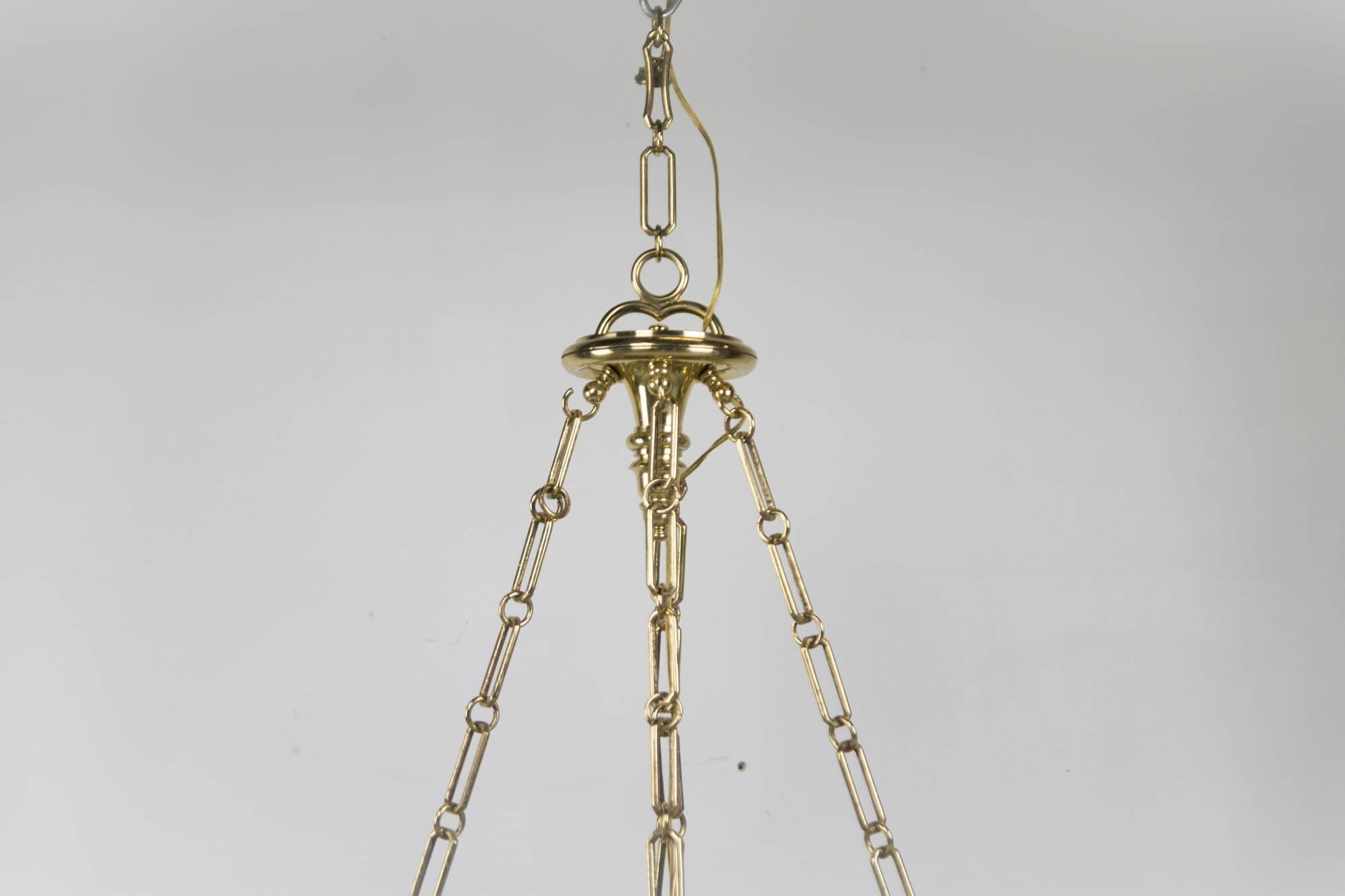 Heavy and robust chandelier by Chapman with eight candlestick lights, hung from chain in stunning restored brass.