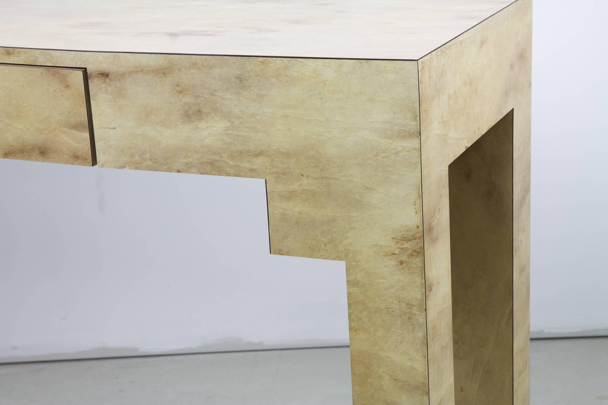 Striking laminated angular console in faux goatskin with a concealed drawer at front.