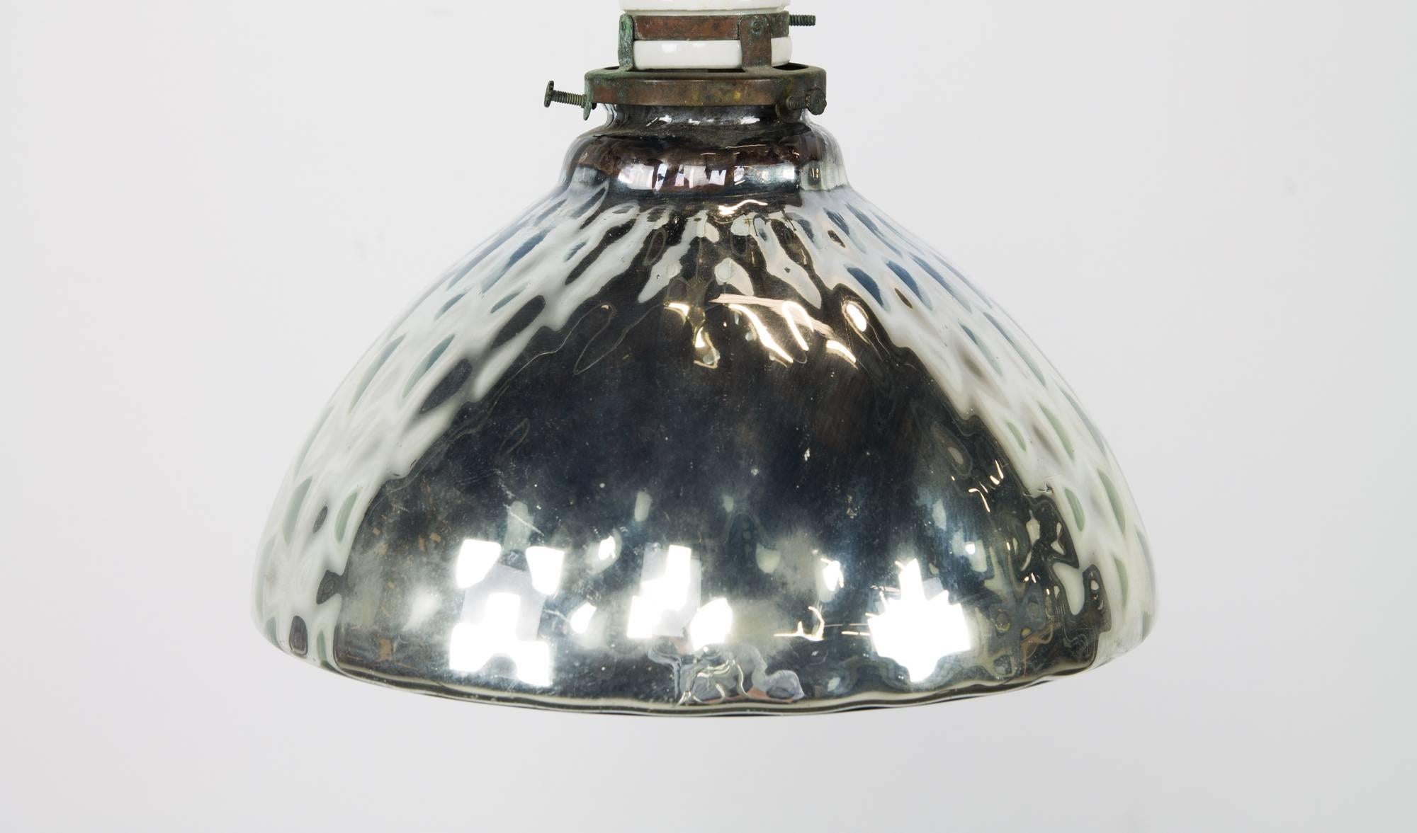 A stunning Industrial 'X-Ray' pendant with original brass hardware, porcelain fixture, and mirrored mercury glass shade featuring double-walled silvered glass for high reflectivity, and a quilting pattern for increased diffusion.