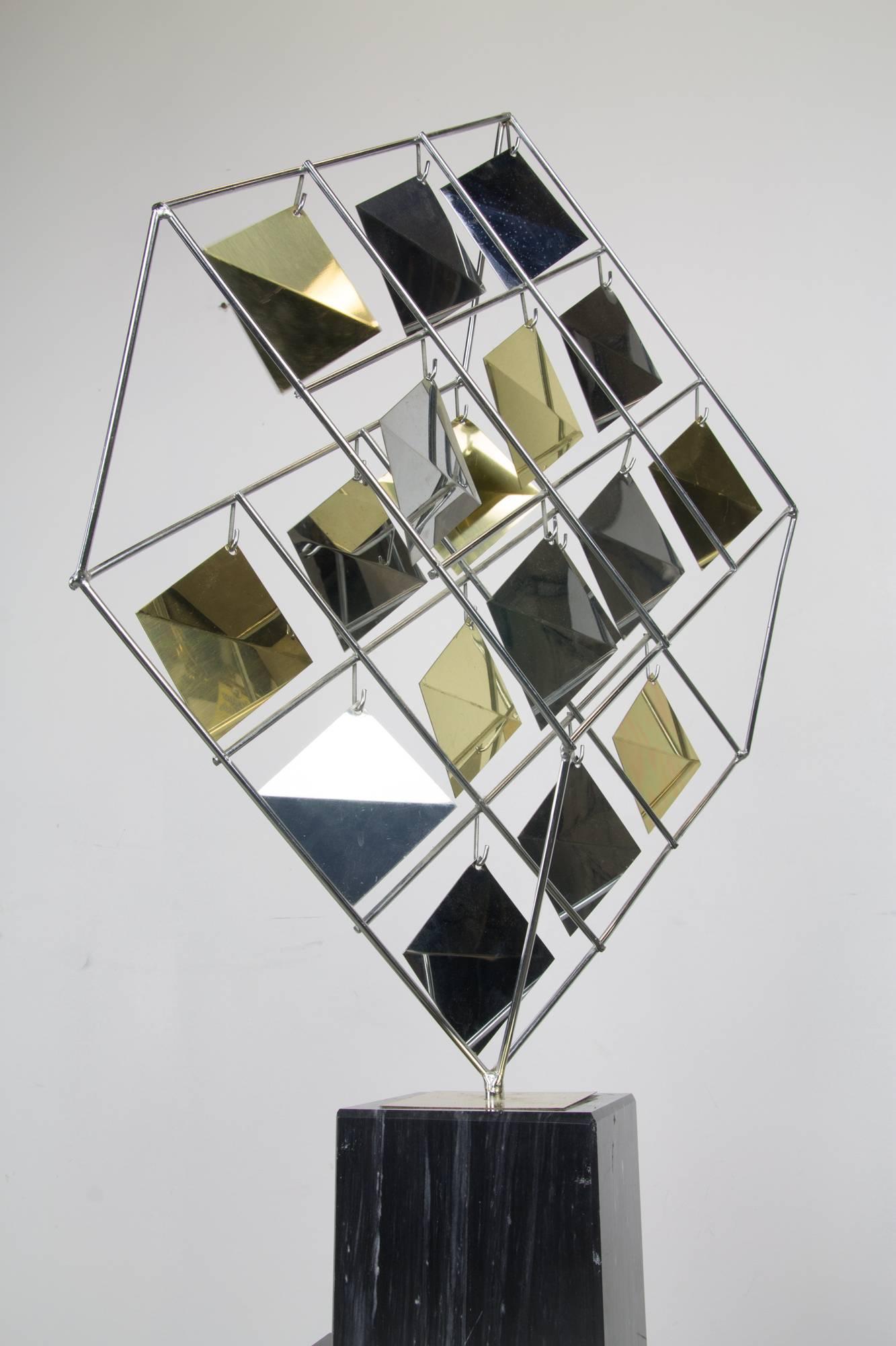 A scarce sculpture by Curtis Jere with two planes holding interchangeable brass and chrome squares, creating the optical effect of a suspended cube. The sculpture sits in a rectangular marble base. Full width is 18.5 in.