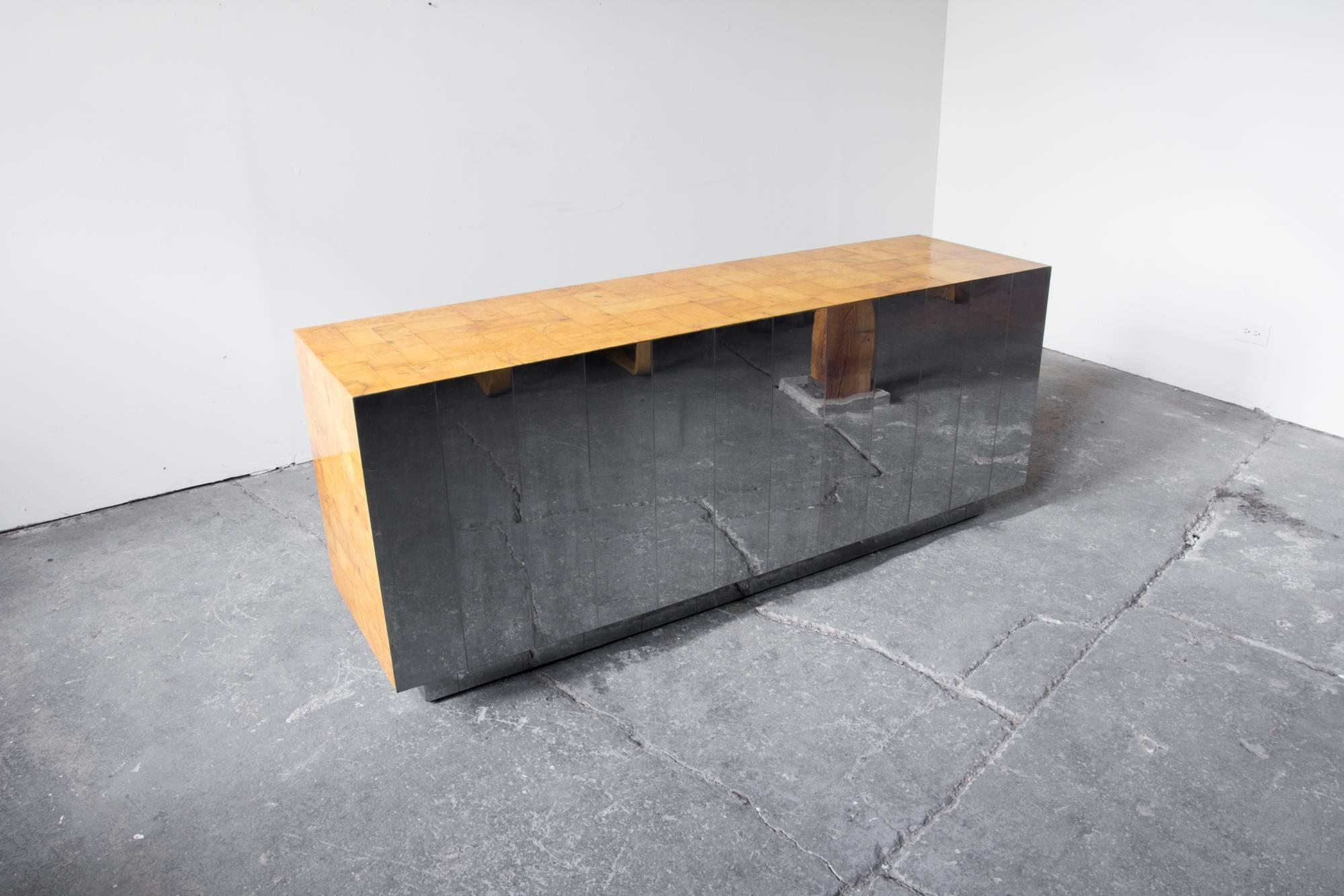 A stunning Paul Evans cabinet or credenza adorned in figural burl veneer and mirrored chrome tiles at the back. The cabinet is lifted from the ground on a well proportioned platform base. Its mirrored back at once lightens the bold presence and