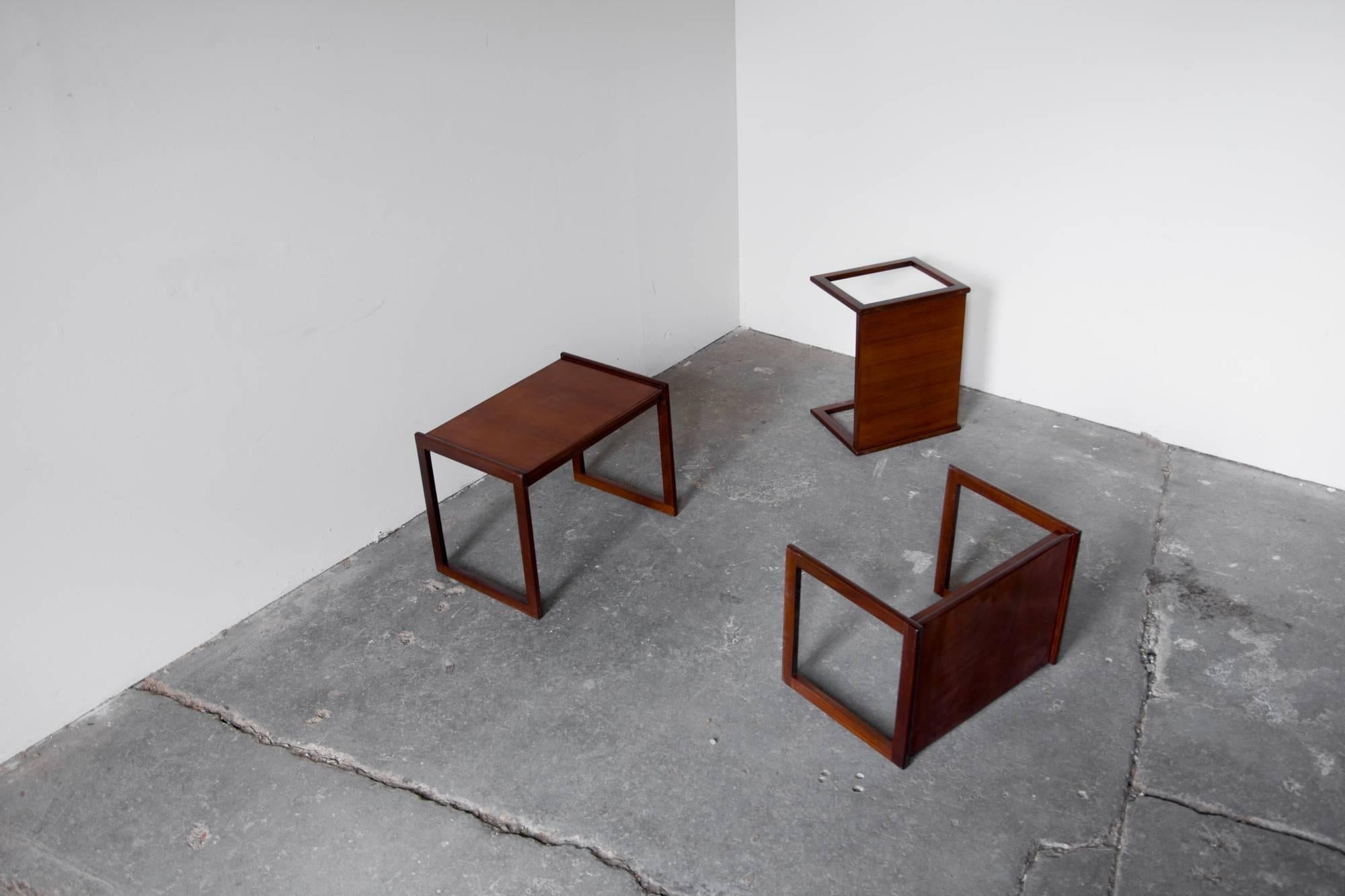 Set of three nesting tables by Punch Design Inc., rectangular sled legs rise slightly above the tabletop, forming a small lip, teak veneer wraps over the surface and around the edges.

Measures: Large 18