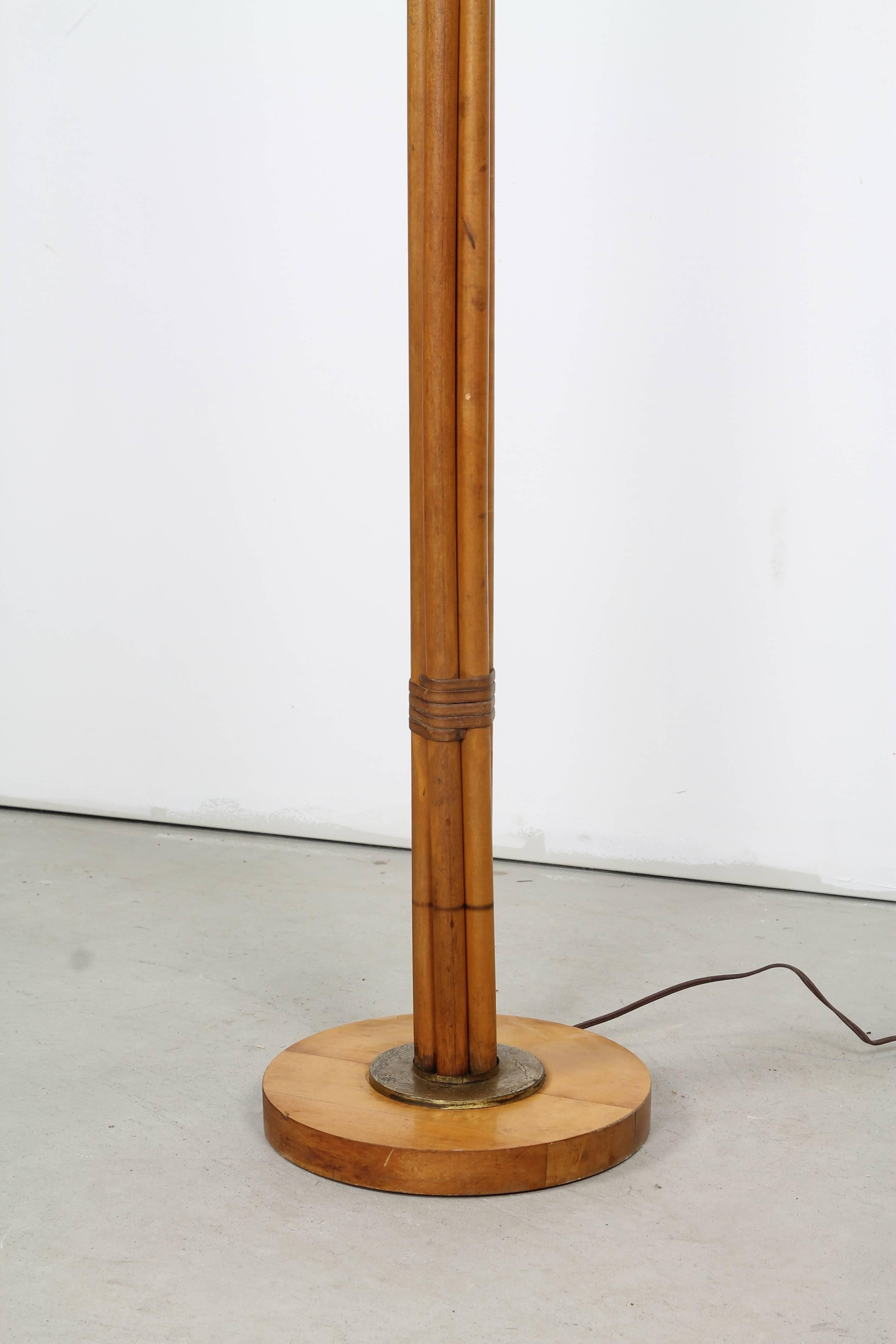 Elegant floor lamp in the manner of Paul Frankl, comprised of bundled bamboo shoots, stemming from a base of wood and brass with pristine original bamboo applique shade. 

Shade diameter: 18.5