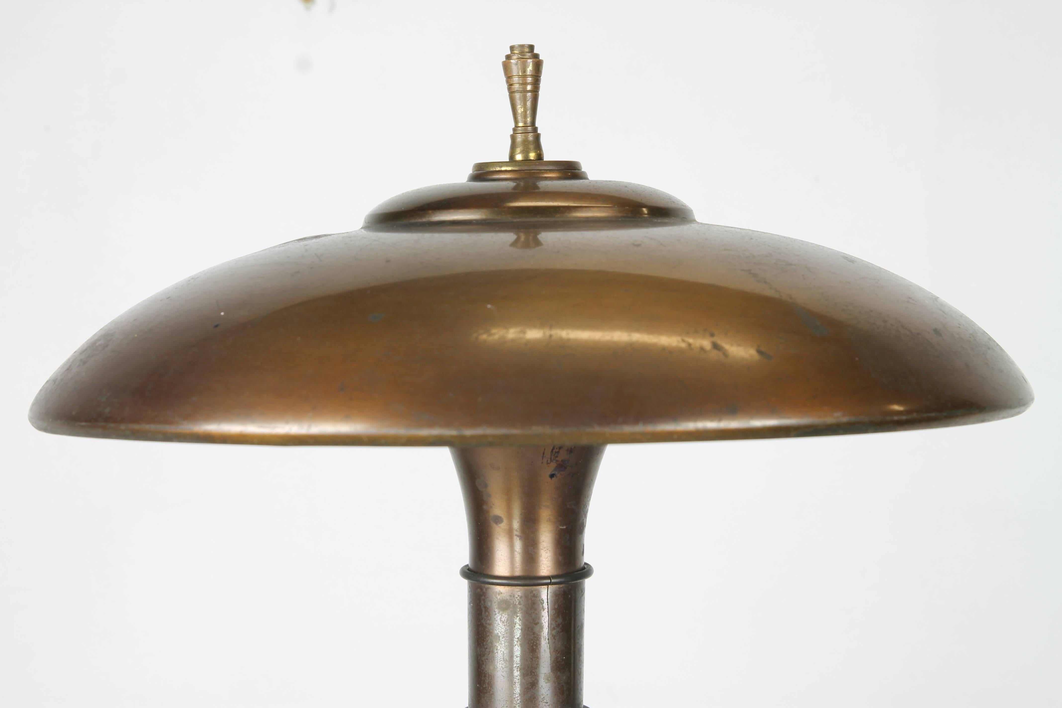 A quintessential American Art Deco table lamp, 'Guardsman Junior' by Bert A. Dickerson for the Faries Mfg. Co. with stacked solid brass skyscraper forms ascending to a spun brass shade and spire-like finial.