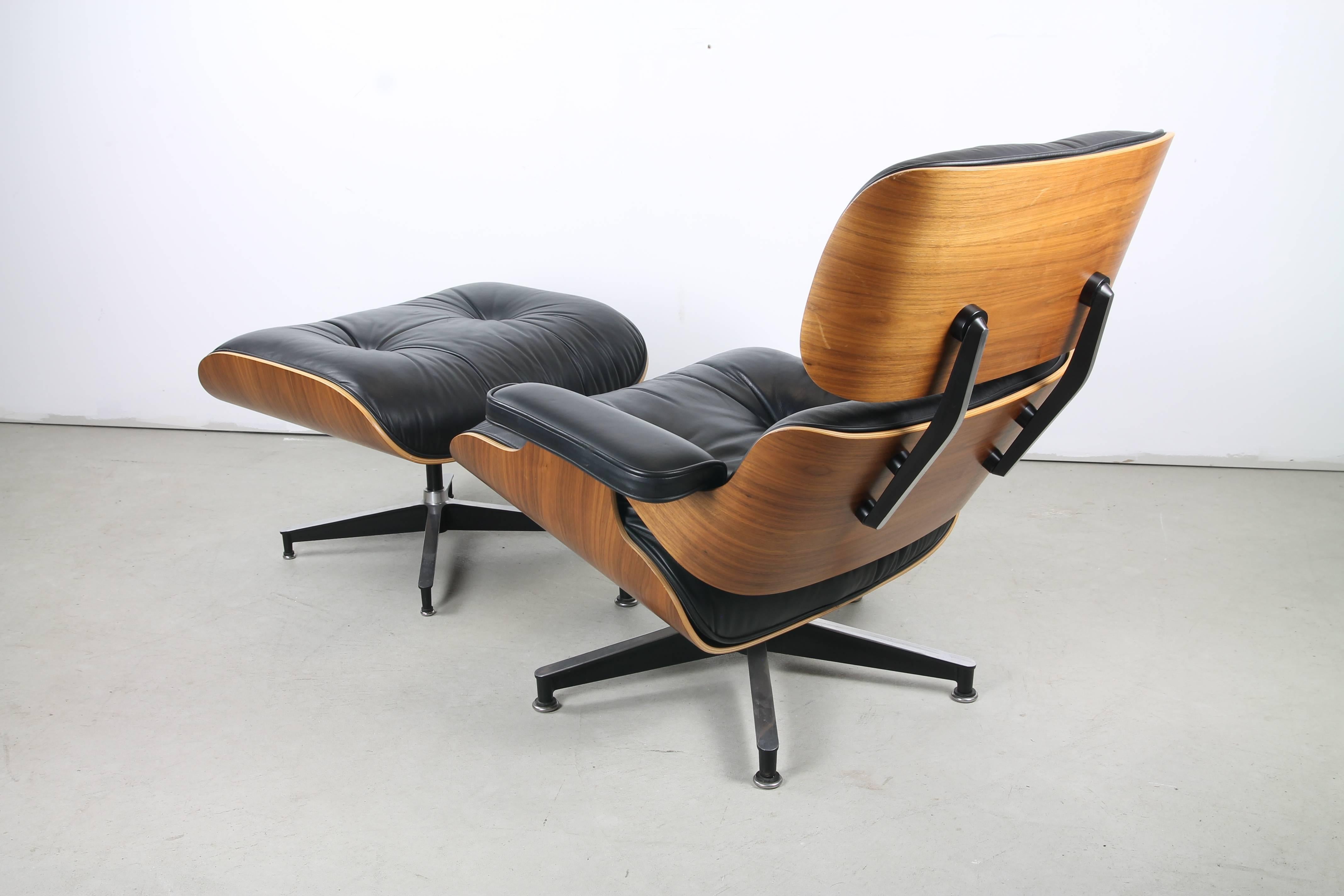 An immaculate 670 lounge and 671 ottoman in walnut by Charles and Ray Eames for Herman Miller, featuring sinuous multi-bend plywood shells framing supple, tufted leather upholstery. The chair swivels on a chromed steel 5-point base. The ottoman is