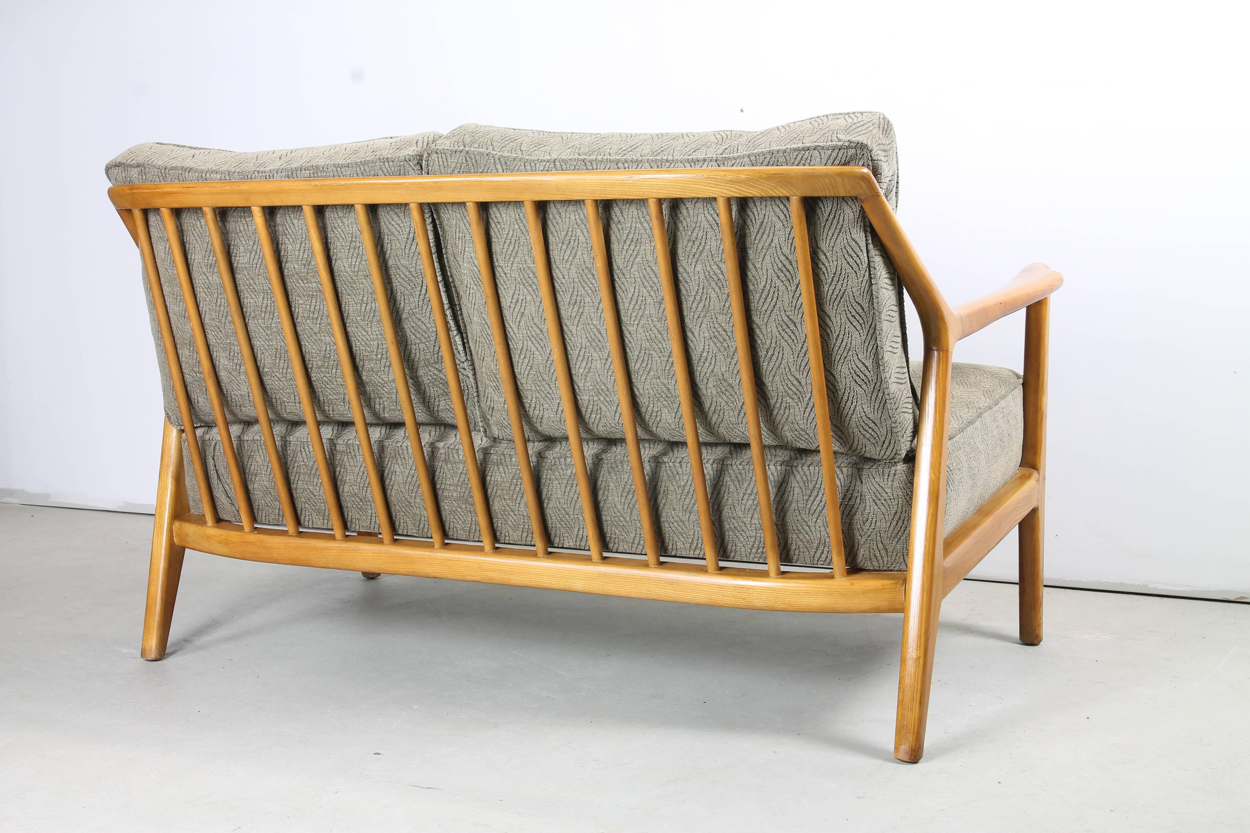 A sculptural and organic formed settee in solid oak by Jack van der Molen for Jamestown Lounge co, featuring a fixed seat cushion and two loose cushions against a broad spindle back.