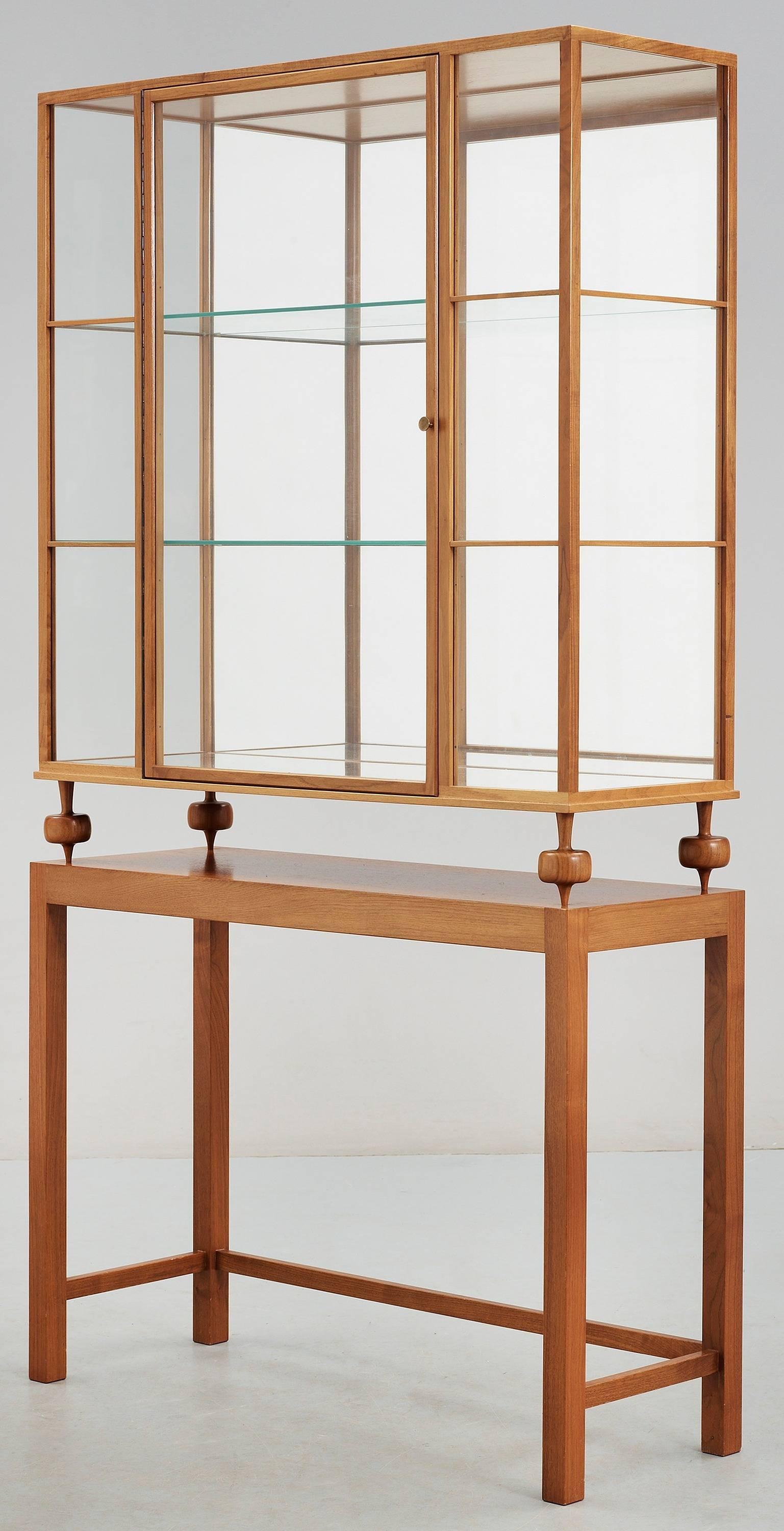 This display case from 1946 was the last glass cabinet designed by Josef Frank for Svenskt Tenn. It's lightness in design gives it rare elegance. Shelves made of glass, mirror backing gives depth, brass knob.