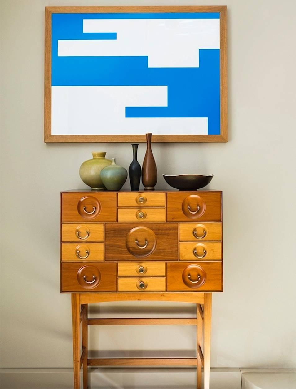 Model 2237, 13 different sized drawers of oak, walnut and mahogany. Sides and top veneered with amboyna root, legs of walnut, pull handles and knobs of brass. 
Frank designed many variations of the cabinet-on-stand form inspired by English and
