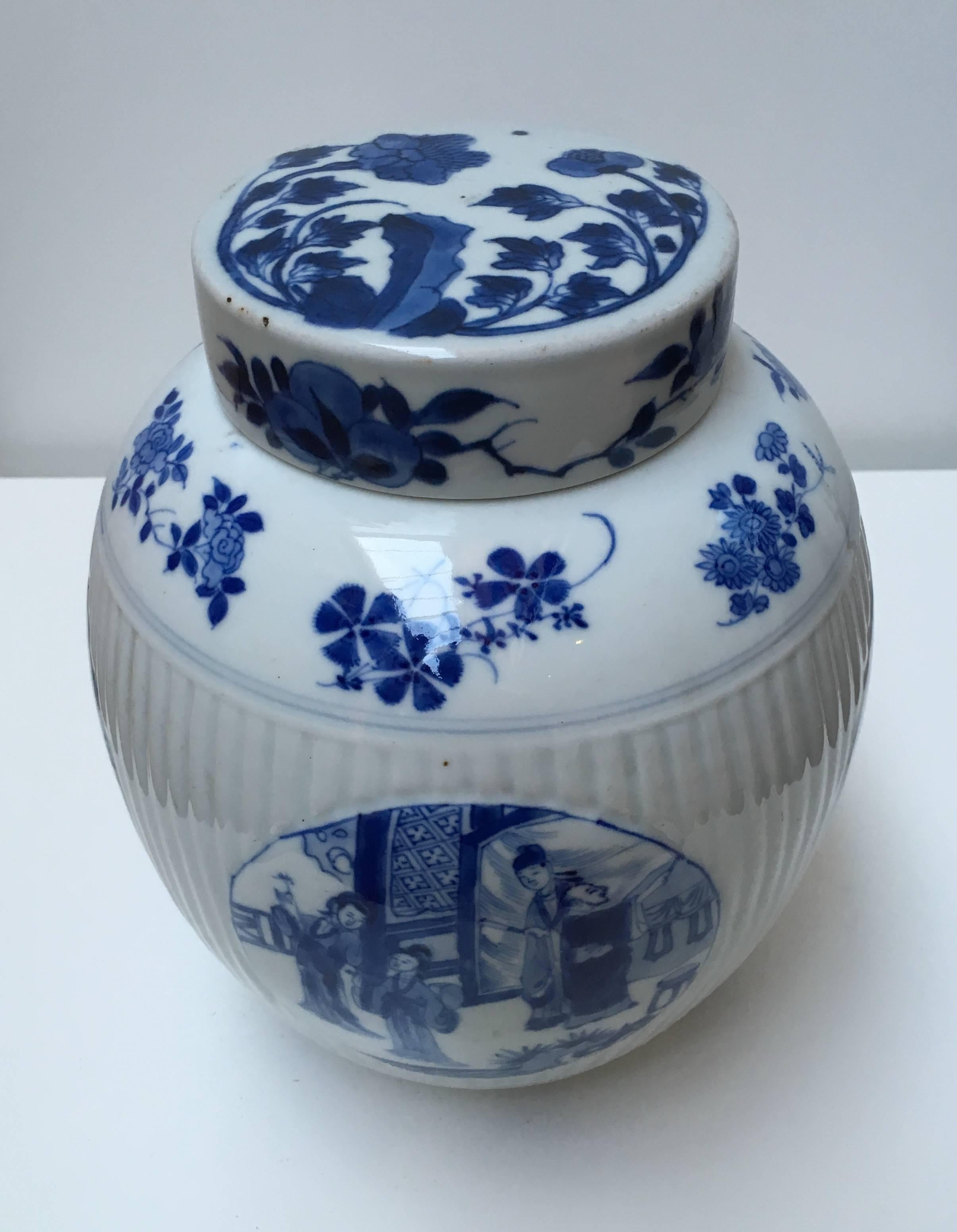 Ovoid, with ribbed middle section, the wide cylindrical cover (matched) over a short unglazed neck, decorated in underglaze blue with four medallions with genre-scenes depicting various persons. The top, bottom and cover decorated with floral